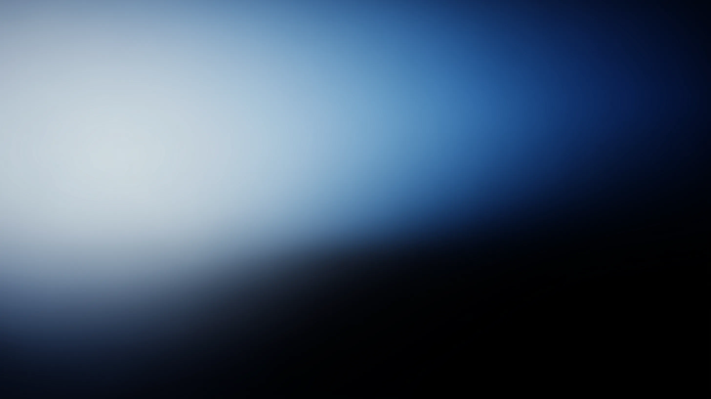 Woman working on a laptop computer at a table in a bright room.