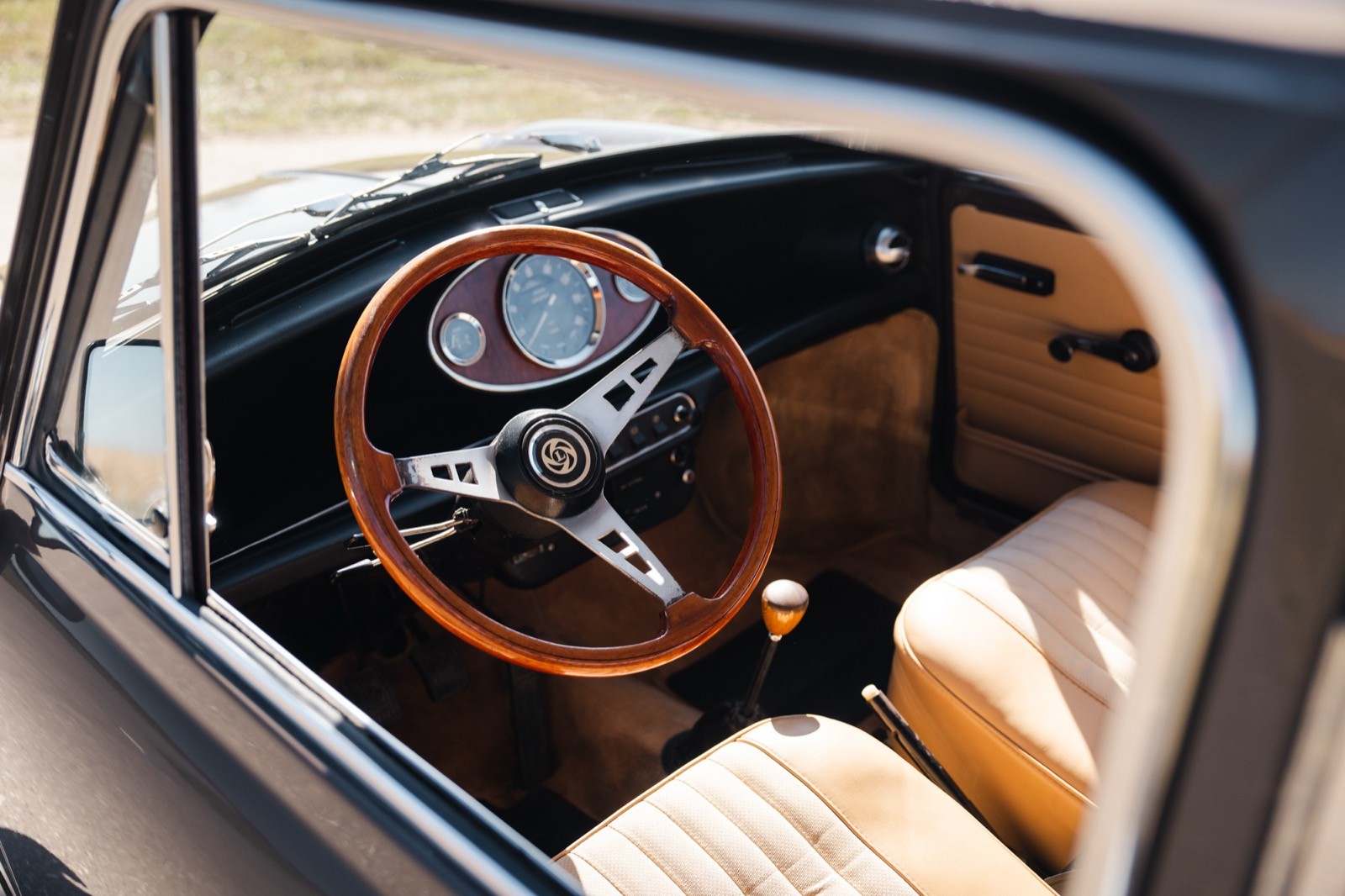 Close-up view of a vintage car's interior, featuring a wooden steering wheel and classic dashboard.