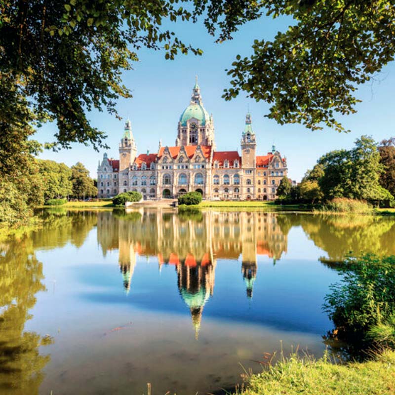 New York City skyline at twilight featuring the Empire State Building and other skyscrapers illuminated against a purple-blue sky.