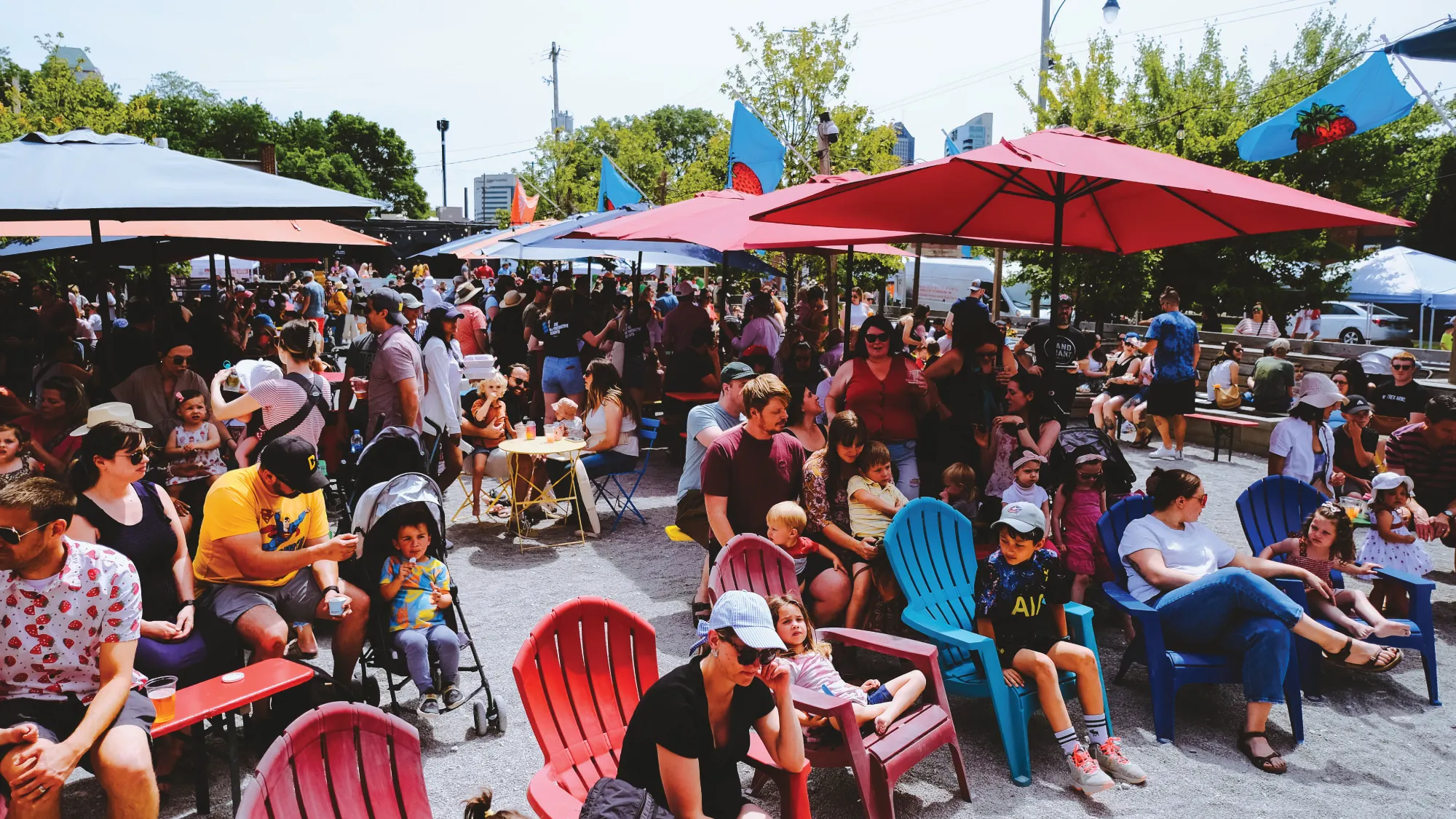 Crowded beer garden with red and blue chairs and umbrellas