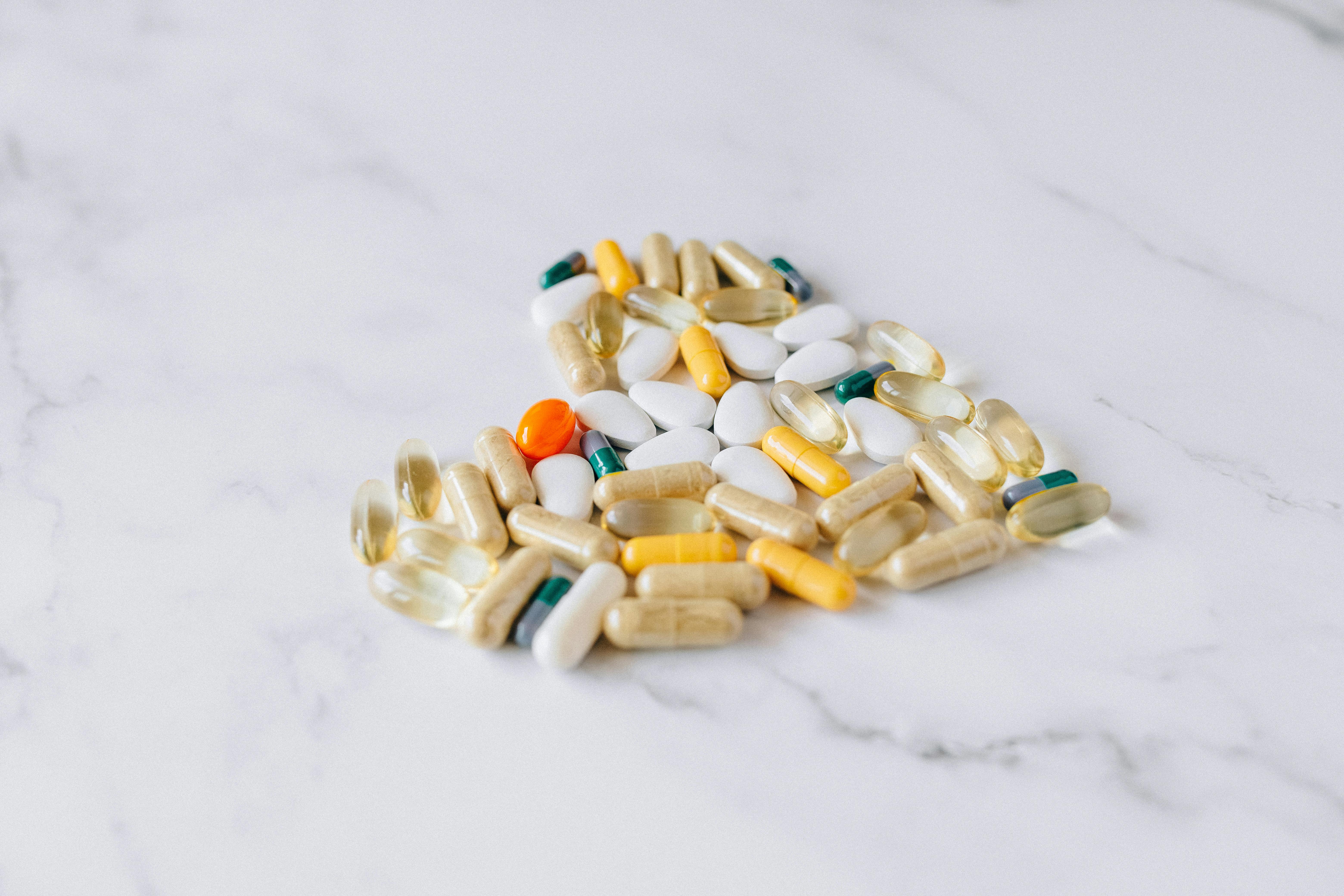 Assorted prescription medication capsules and tablets arranged on a marble surface, representing pharmacy prior authorization for specialty drugs
