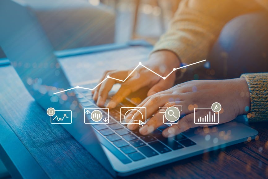 Businesswoman working on a laptop, analyzing graphs and business icons to enhance her marketing strategy.