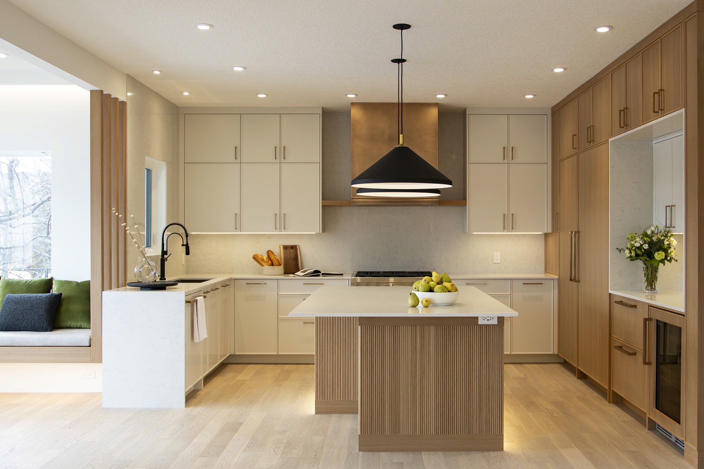 Springbank Hill Kitchen with two-toned custom cabinets in warm white and a light, warm wood, light countertops, dark island lights, and dark faucet.