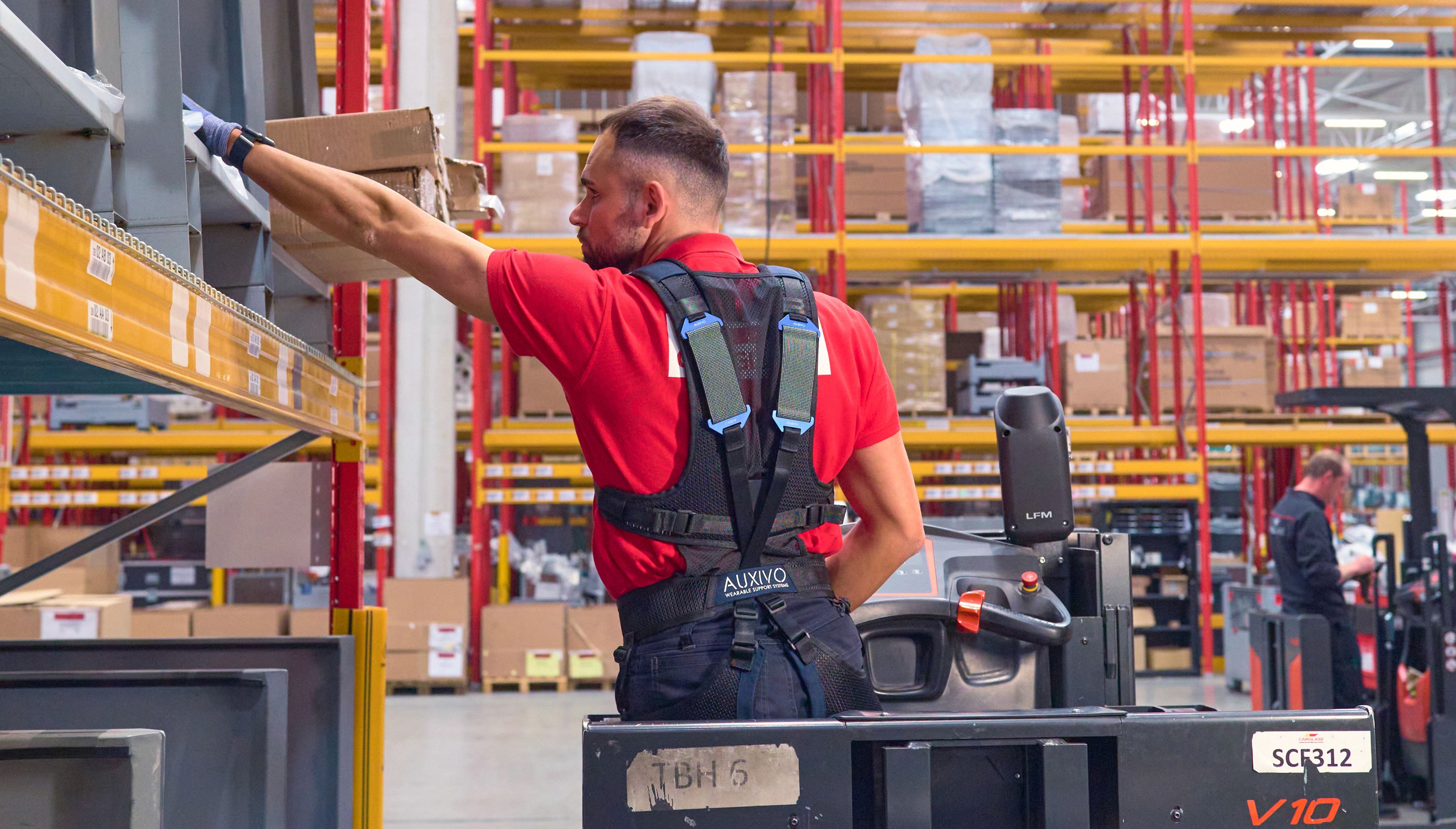 Travailleur en entrepôt utilisant un exosquelette dorsal LiftSuit pour réduire la fatigue lors de tâches de levage.