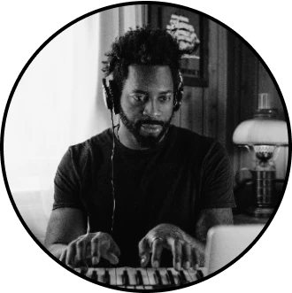 A musician wearing headphones is playing a synthesizer during an online jam live session from home.