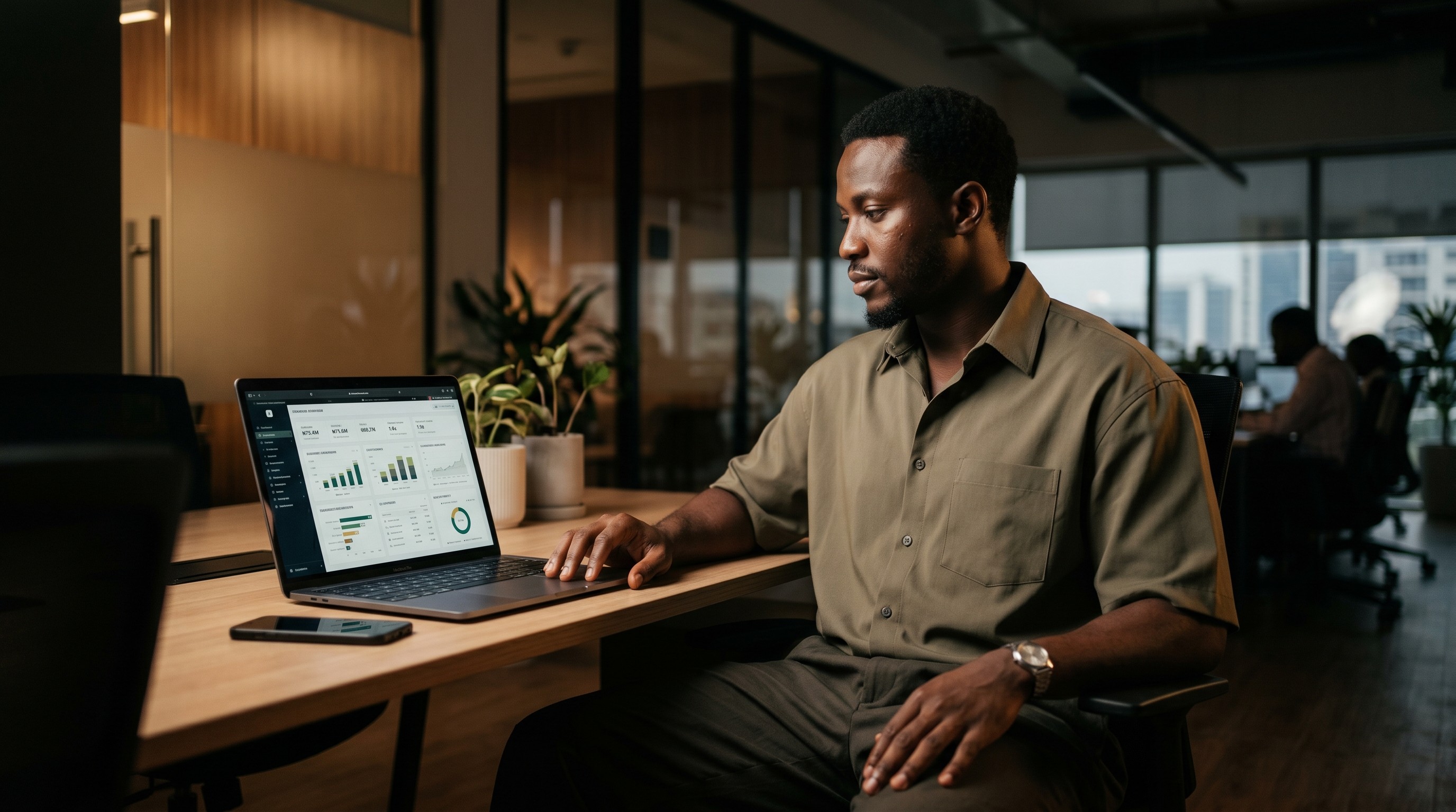 A man reviews financial dashboards on a laptop at an office desk