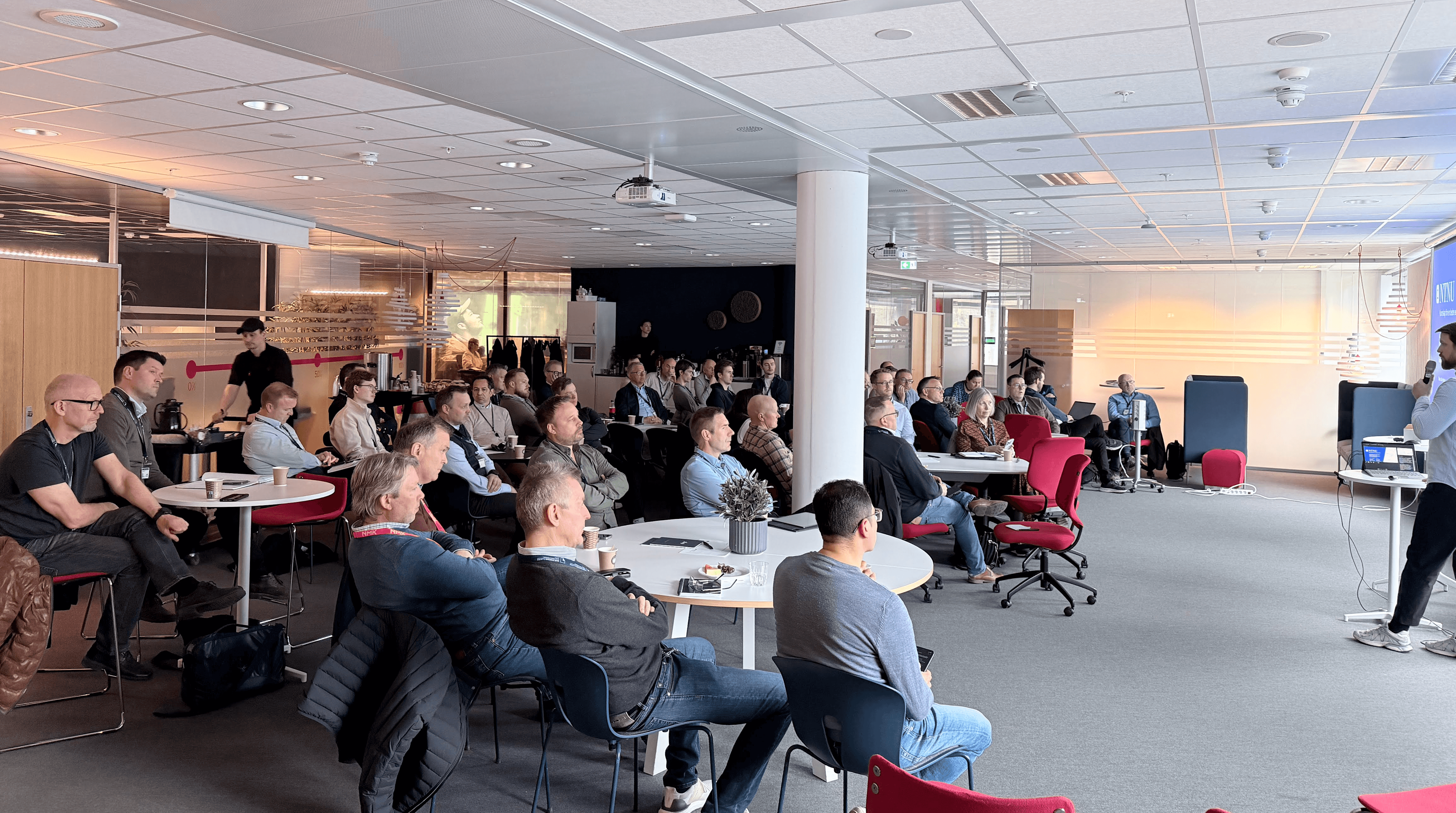 A person wearing a virtual reality headset stands in front of multiple screens, engaged in a digital experience.