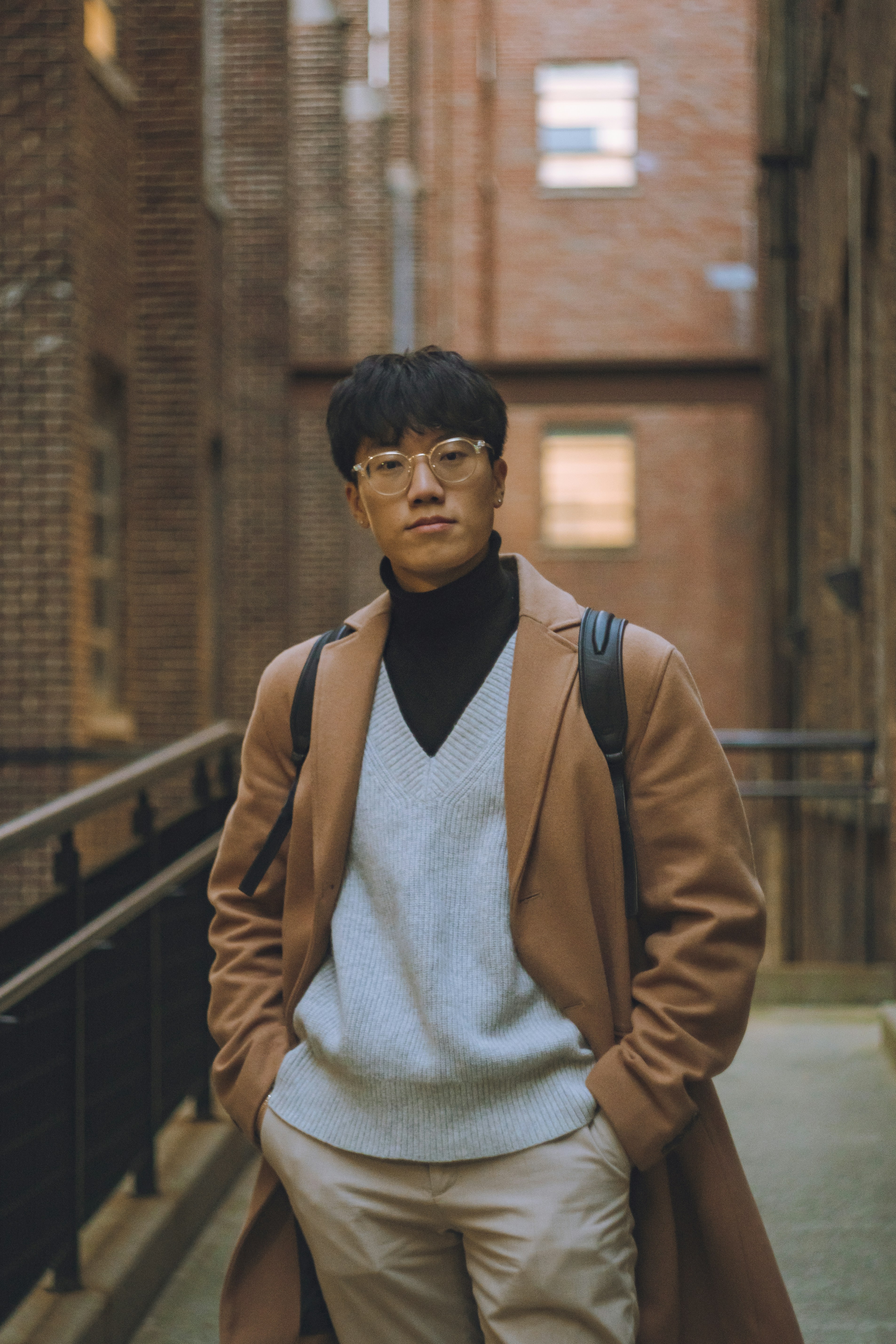 A stylish man poses in an urban alleyway.