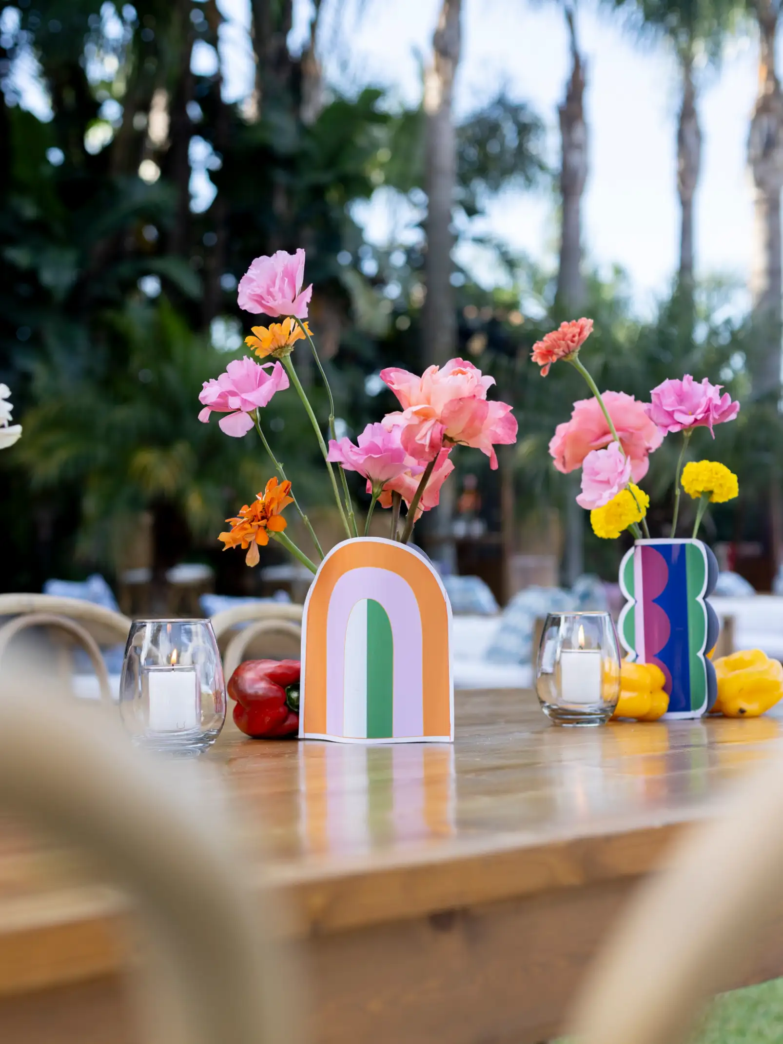 Decoración de mesa con floreros coloridos y flores brillantes para evento moderno, transmitiendo energía lúdica y estilo contemporáneo.