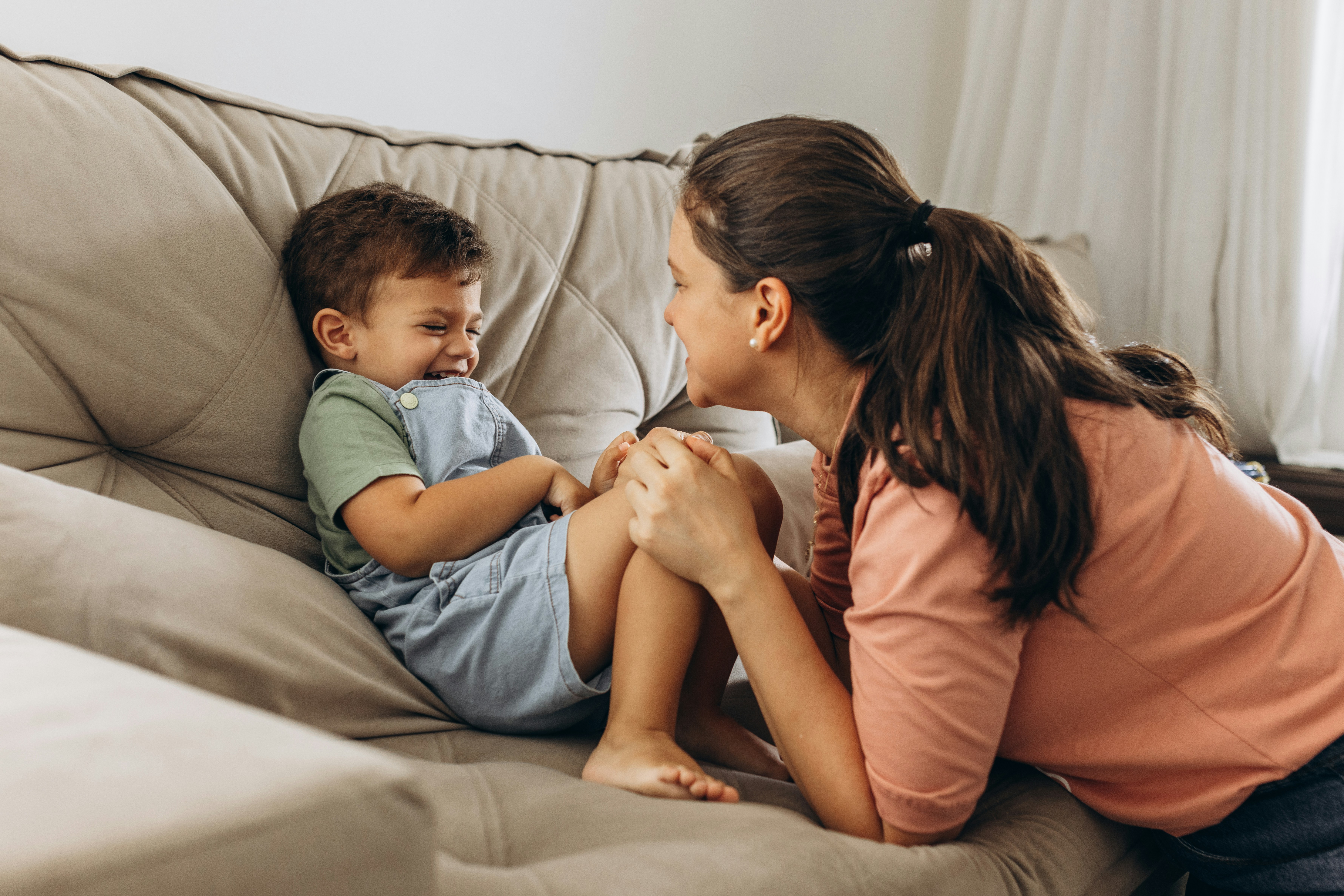 a woman sitting on top of a couch next to a little boy
