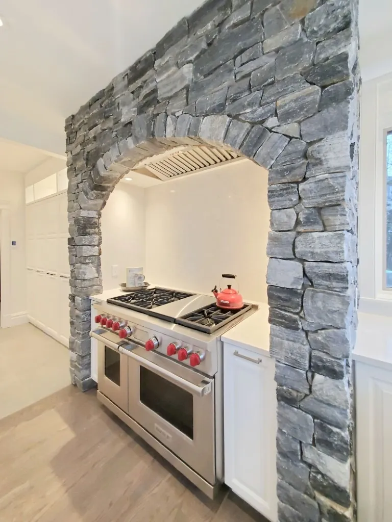 Image of Luxury kitchen design featuring a stone archway, gas range, and modern layout by KHD Homes.