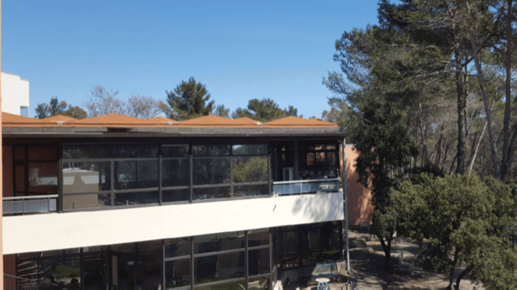 Bâtiment clinique moderne avec une façade contemporaine en verre et blanche, ciel bleu clair, aménagement paysager visible
