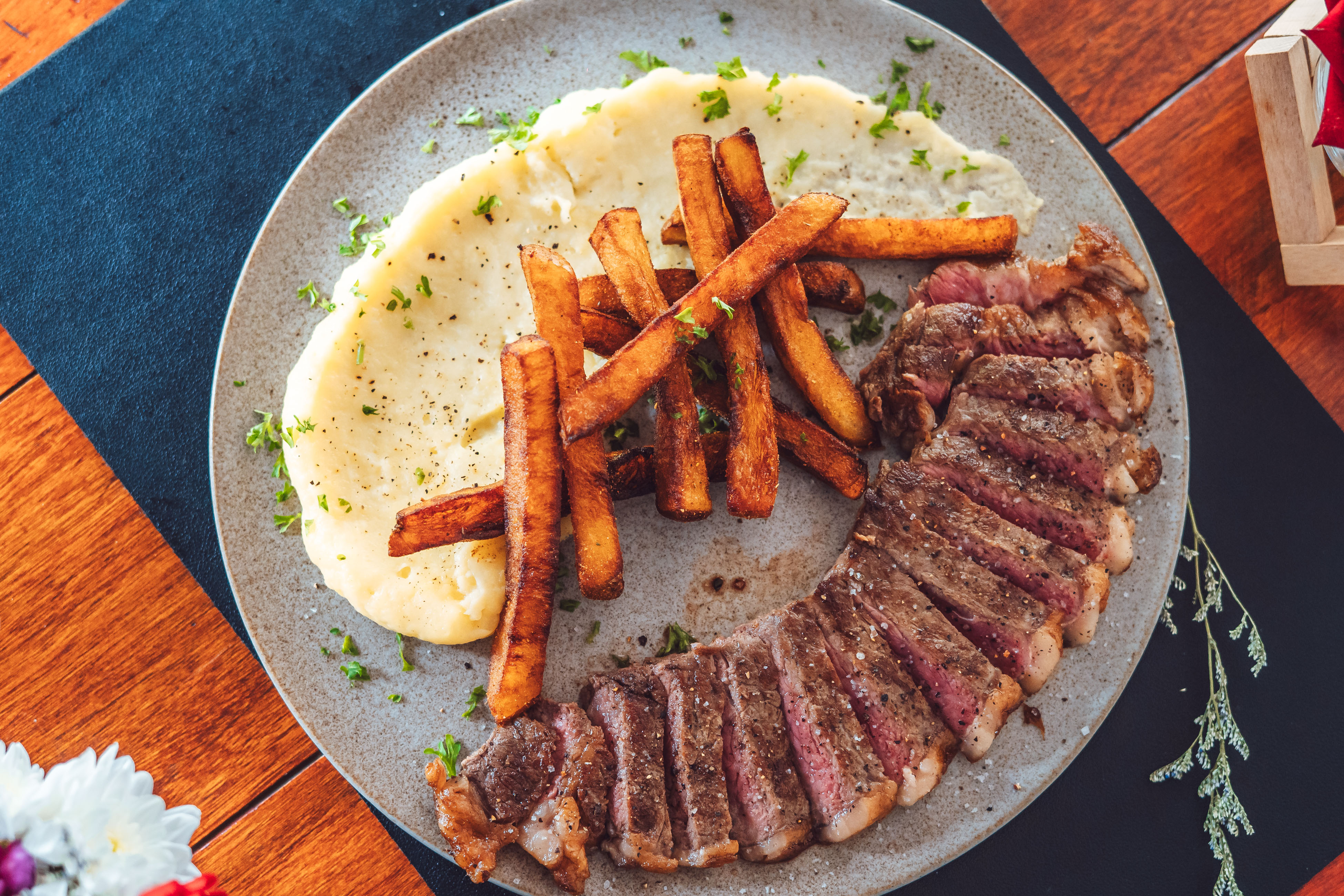 A rustic table set with various traditional pastries and a small bottle, surrounded by green foliage.