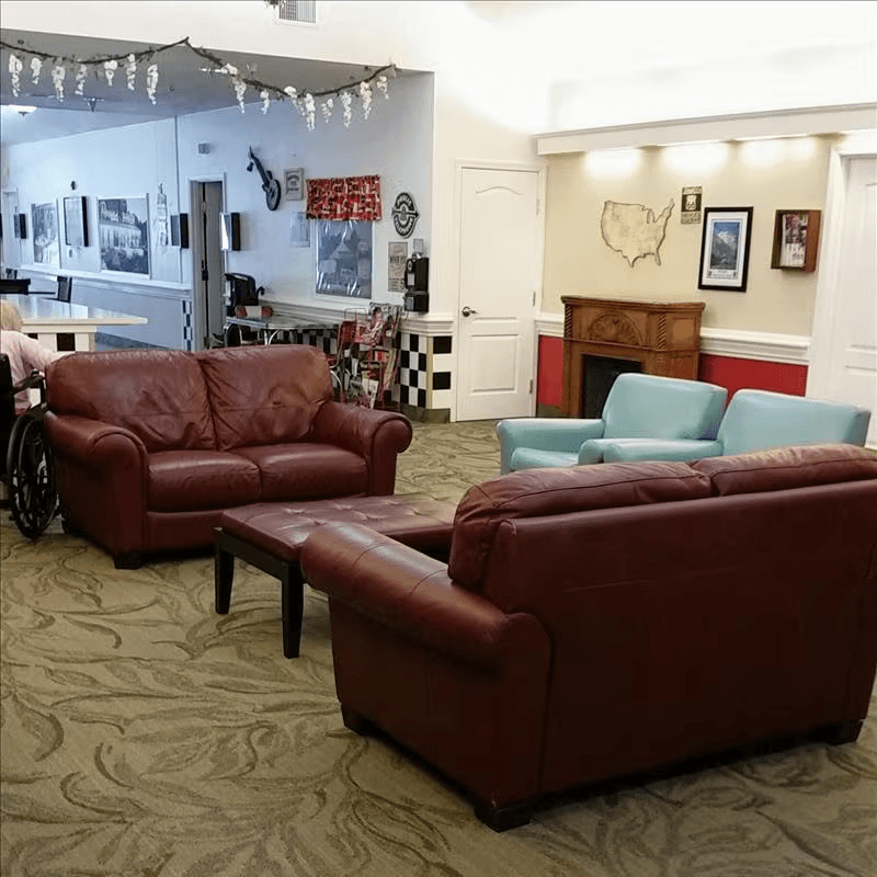 Comfortable communal lounge in a memory care home with couches and natural light for relaxation and social time.