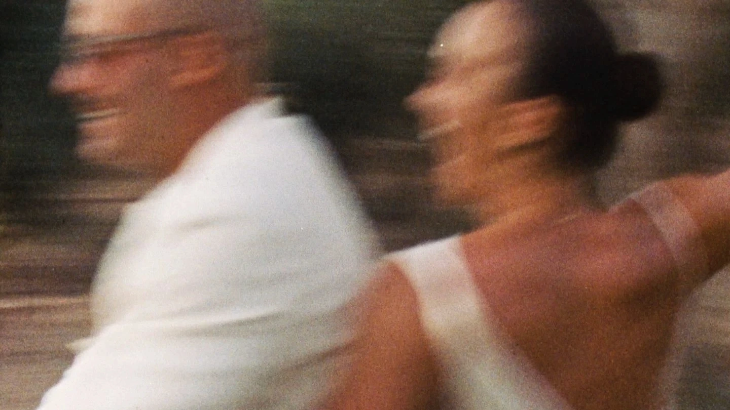 A joyous couple in elegant attire moves with blurred motion, capturing a sense of movement and happiness.