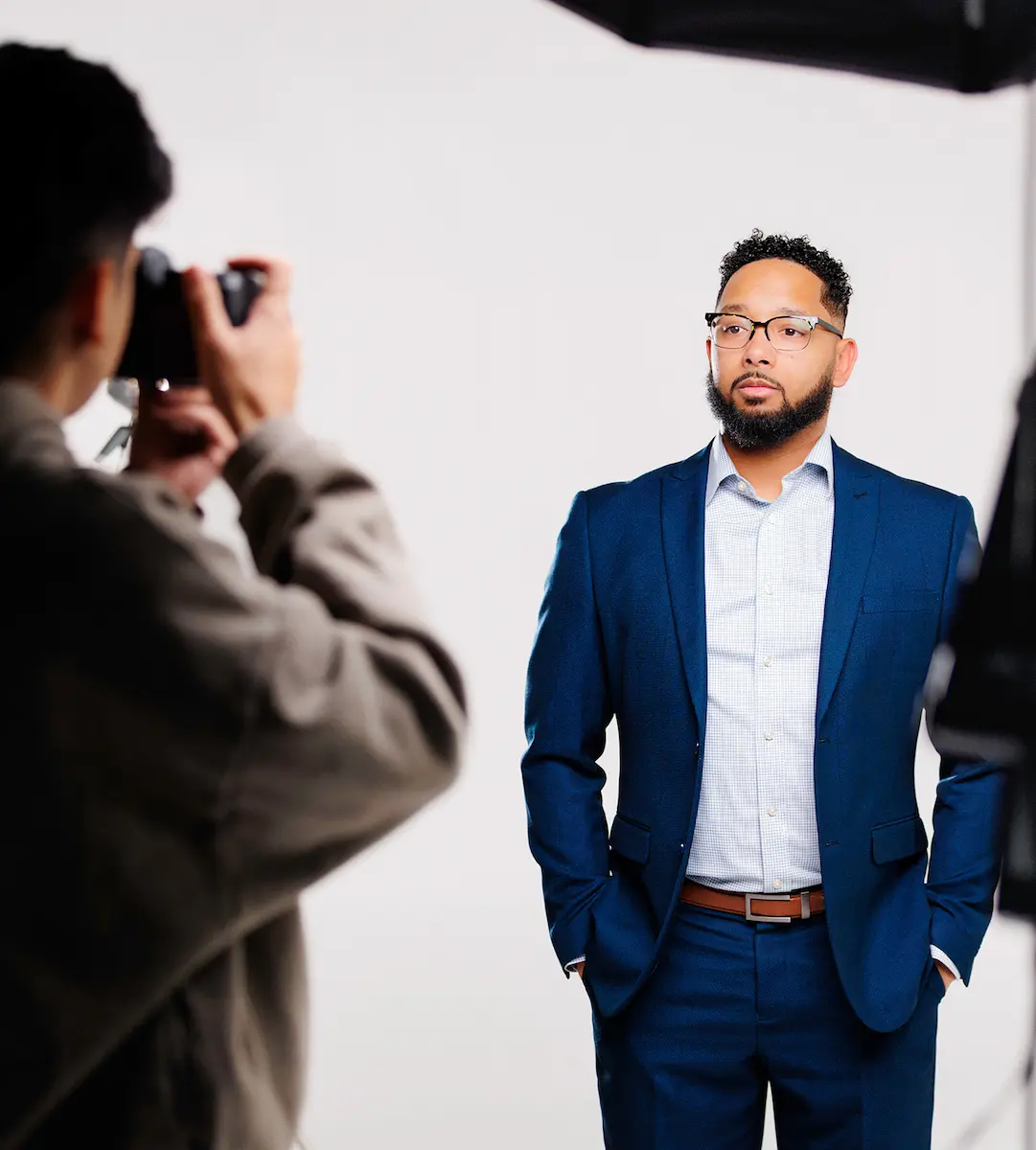 Chris Lewis sits at his office desk wearing a dark suit and glasses, working on a computer. The professional setting conveys focus, expertise, and dedication to helping clients navigate the home loan process at Chris Lewis Home Loans.