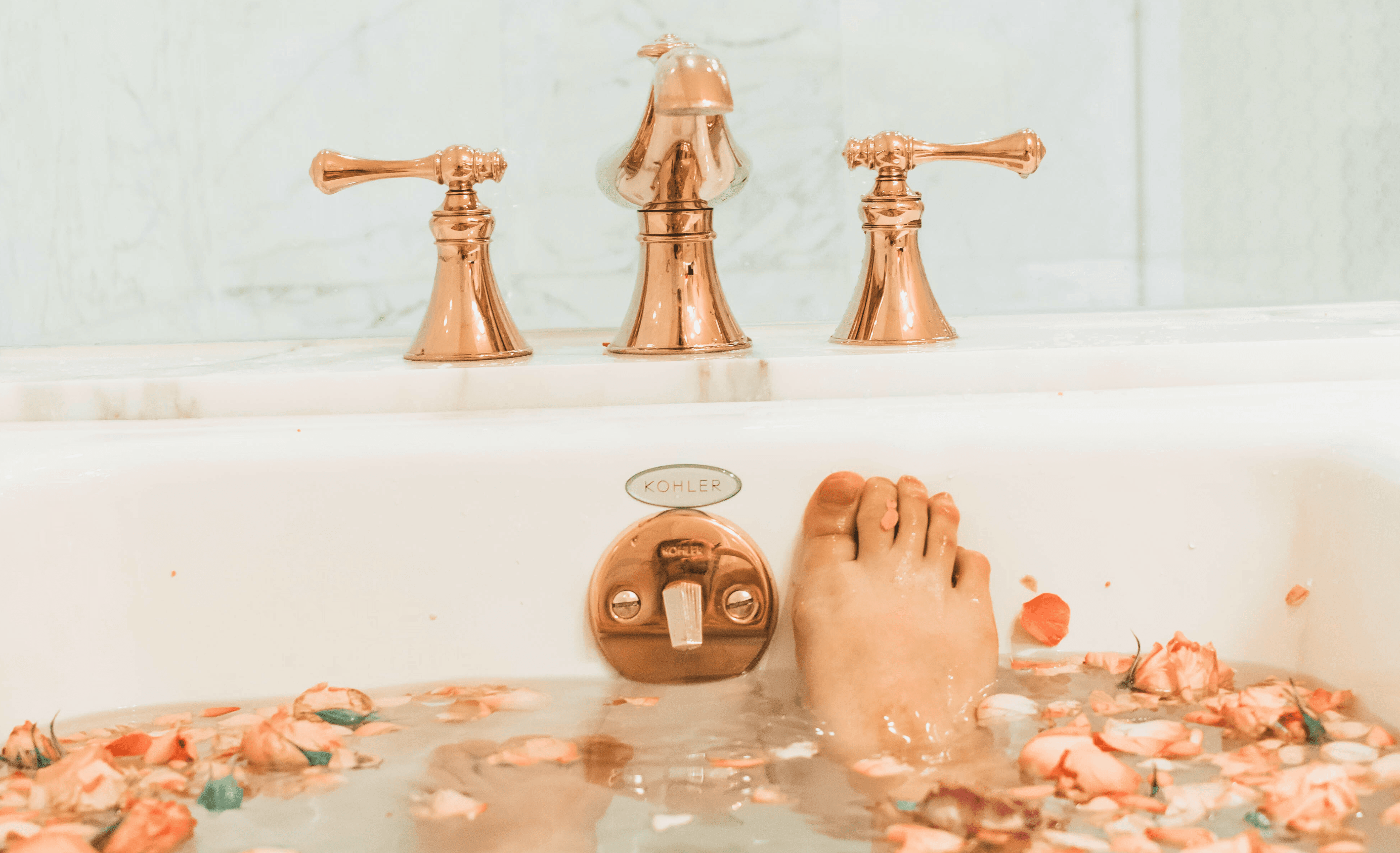 A luxurious bathtub with water and rose petals in it.