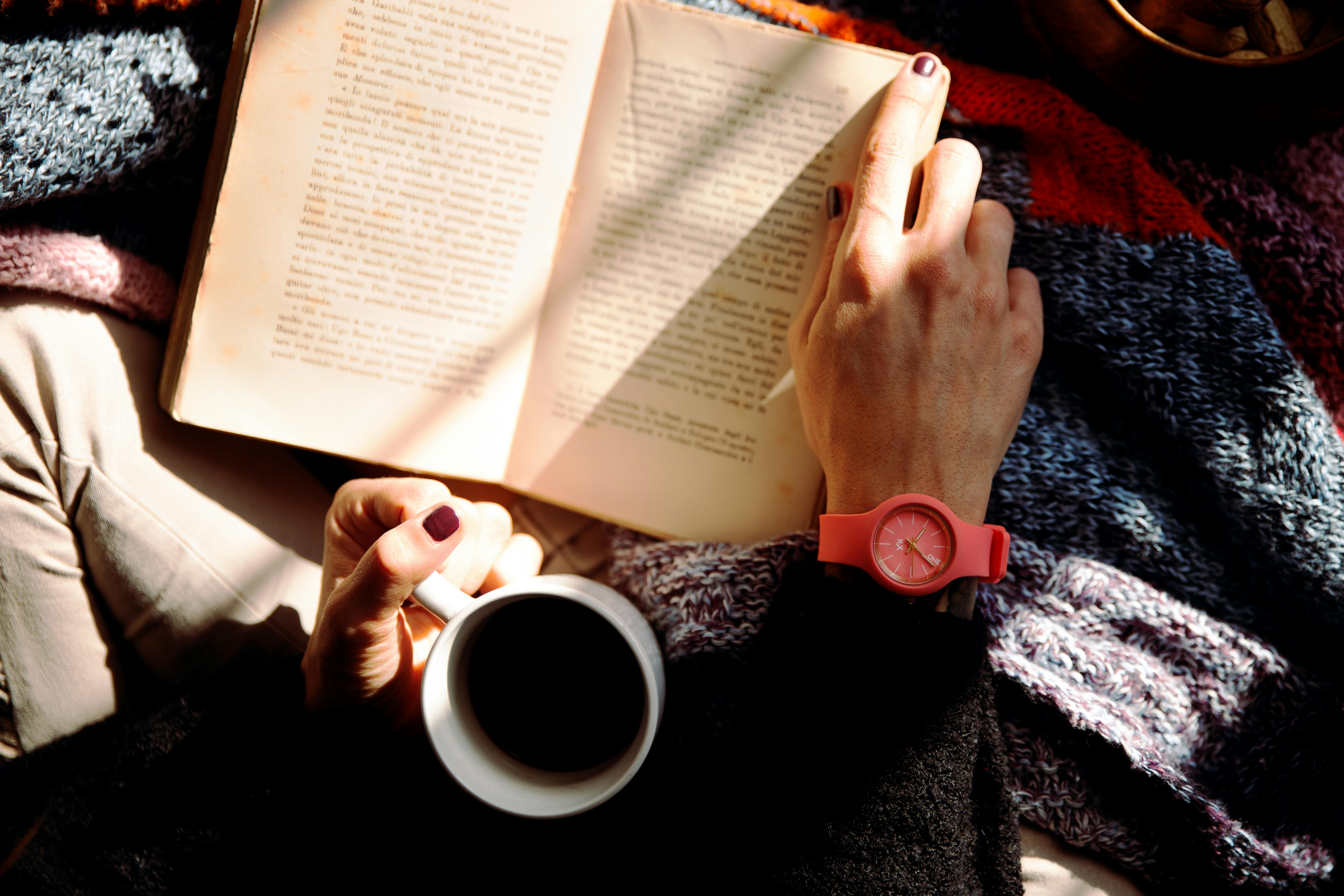 Person reading a book with a cup of coffee