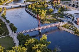 Aerial view of an intersecting dirt pathway forming an X-shape surrounded by lush greenery and arid, rocky terrain, illustrating a contrasting landscape.