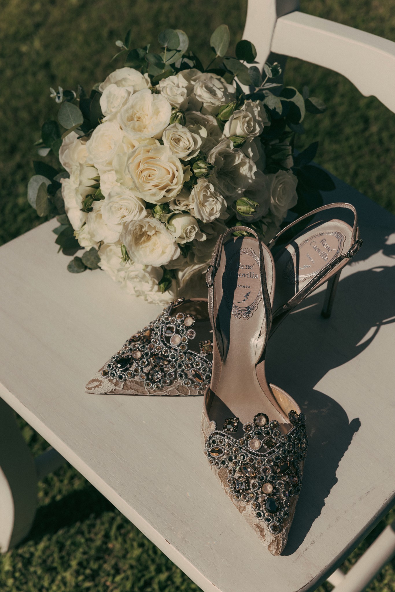 Bouquet di rose avorio e eucalipto con scarpe da sposa glitterate su sedia bianca a Bolgheri
