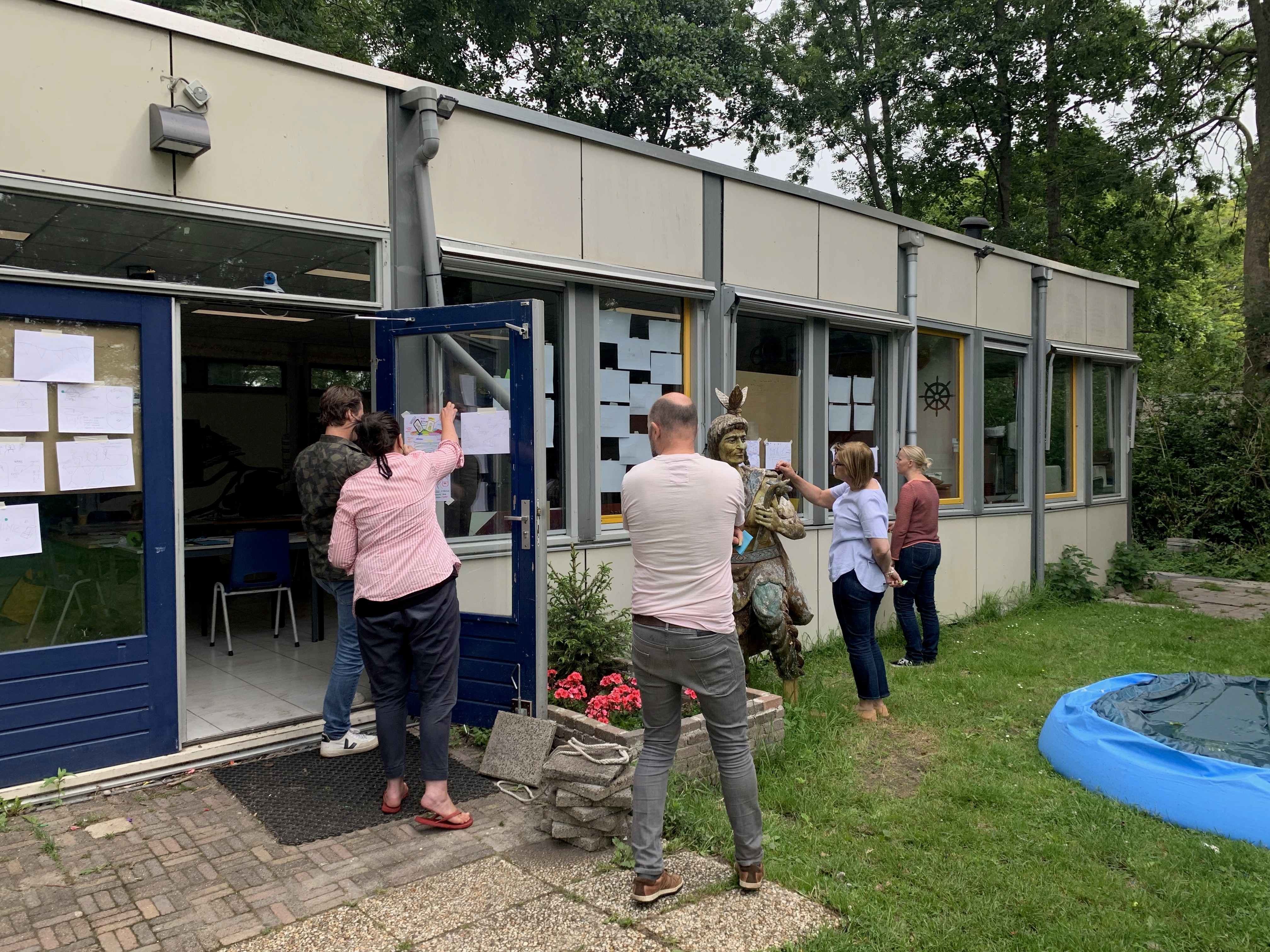 Design sprint participants posting sticky notes on windows during a stakeholder collaboration session