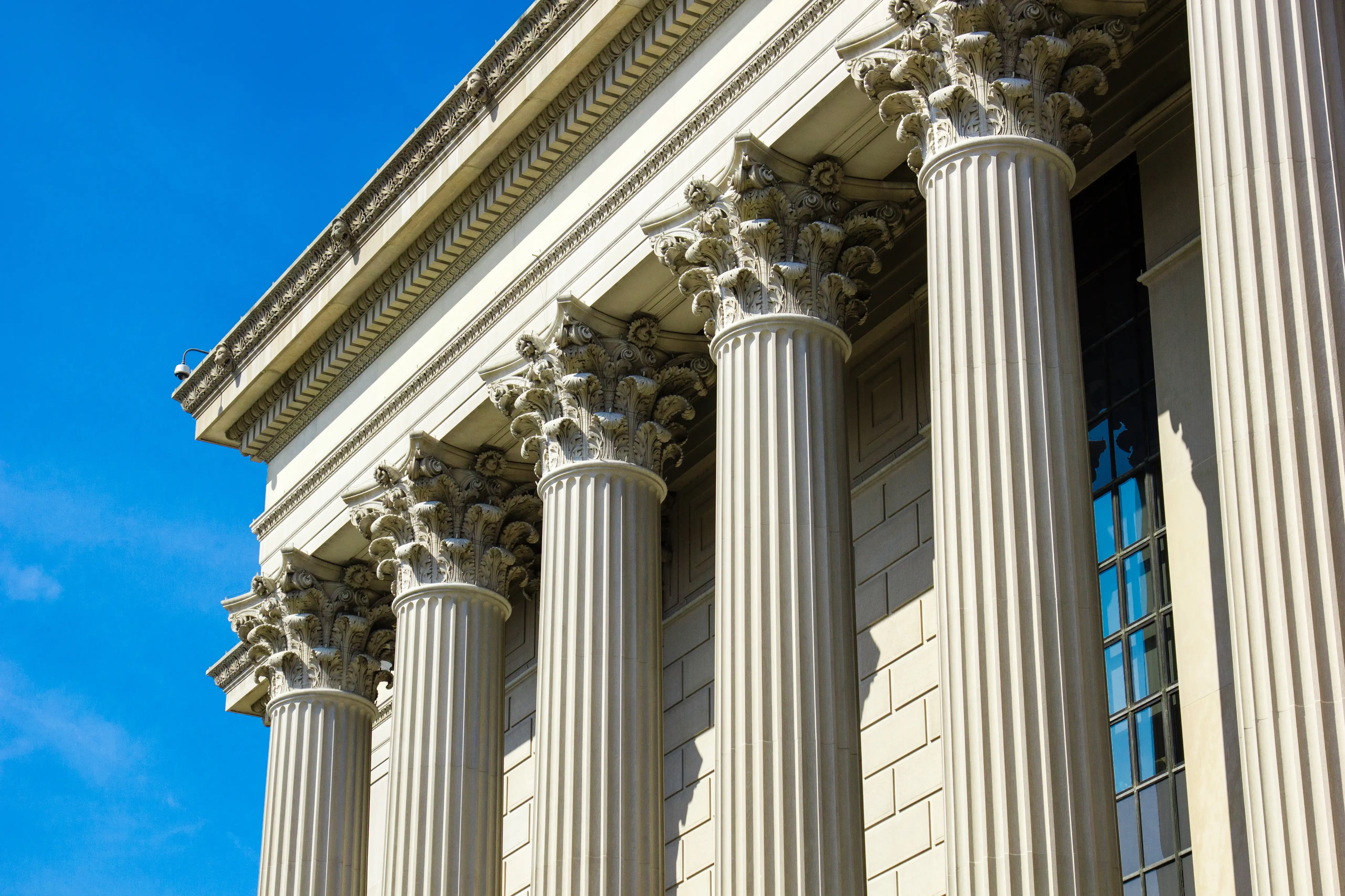 Government building columns under a clear blue sky, illustrating protected whistleblower reporting to law enforcement and regulatory agencies in California