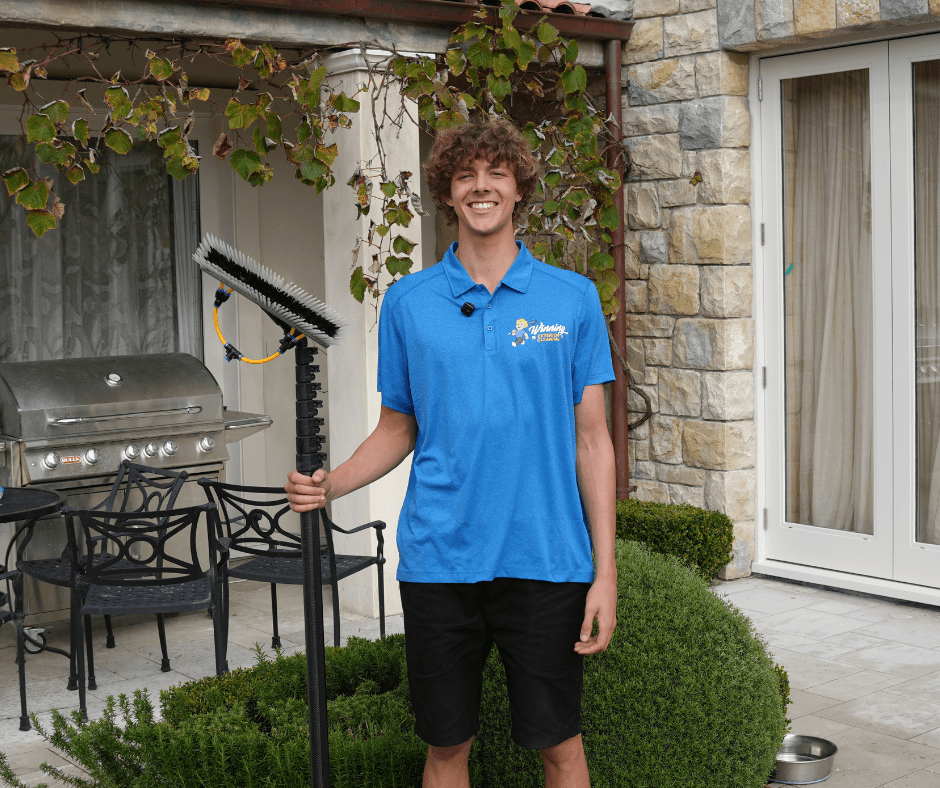 Team member smiling in front of home following completed exterior clean