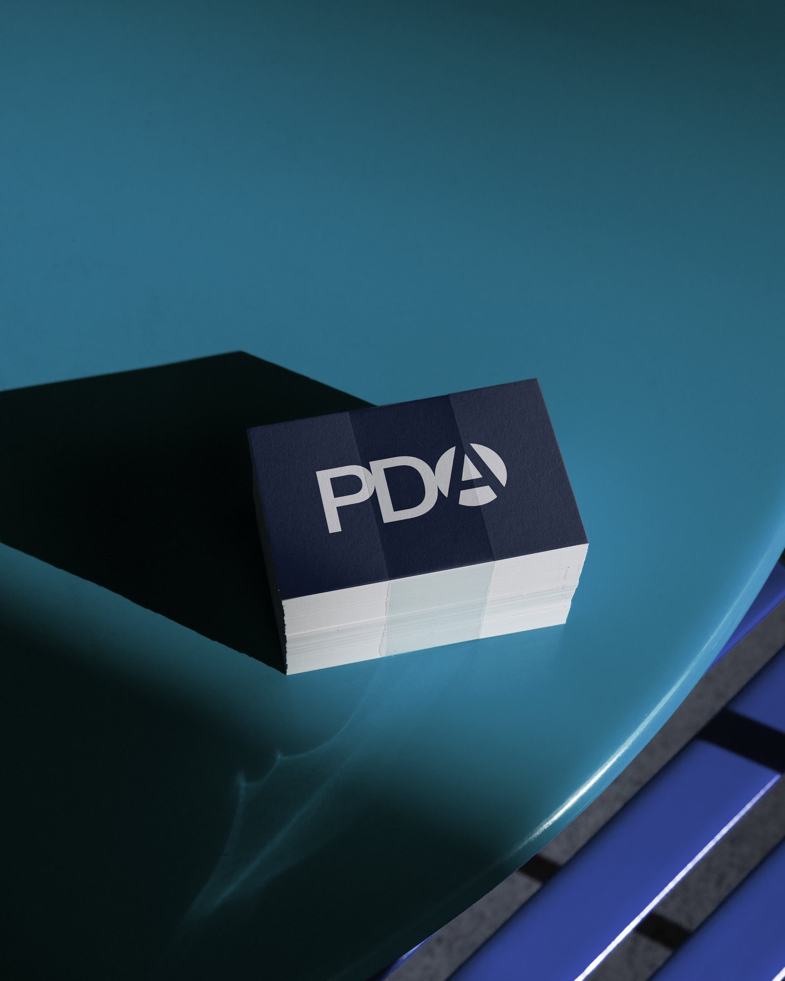 Stack of navy business cards carrying the PDA monogram