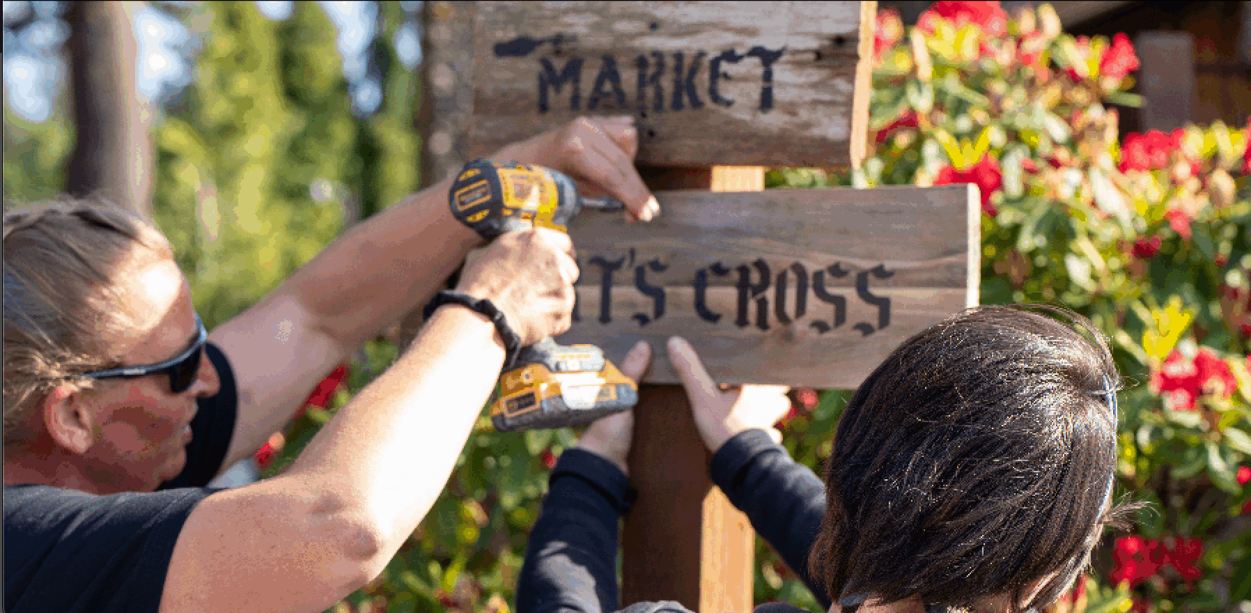 Two people drilling in the Market Cross wood post