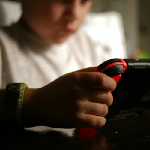 Bambino con smartphone in mano in un momento di disagio, dipendenza tecnologica e difficoltà emotive