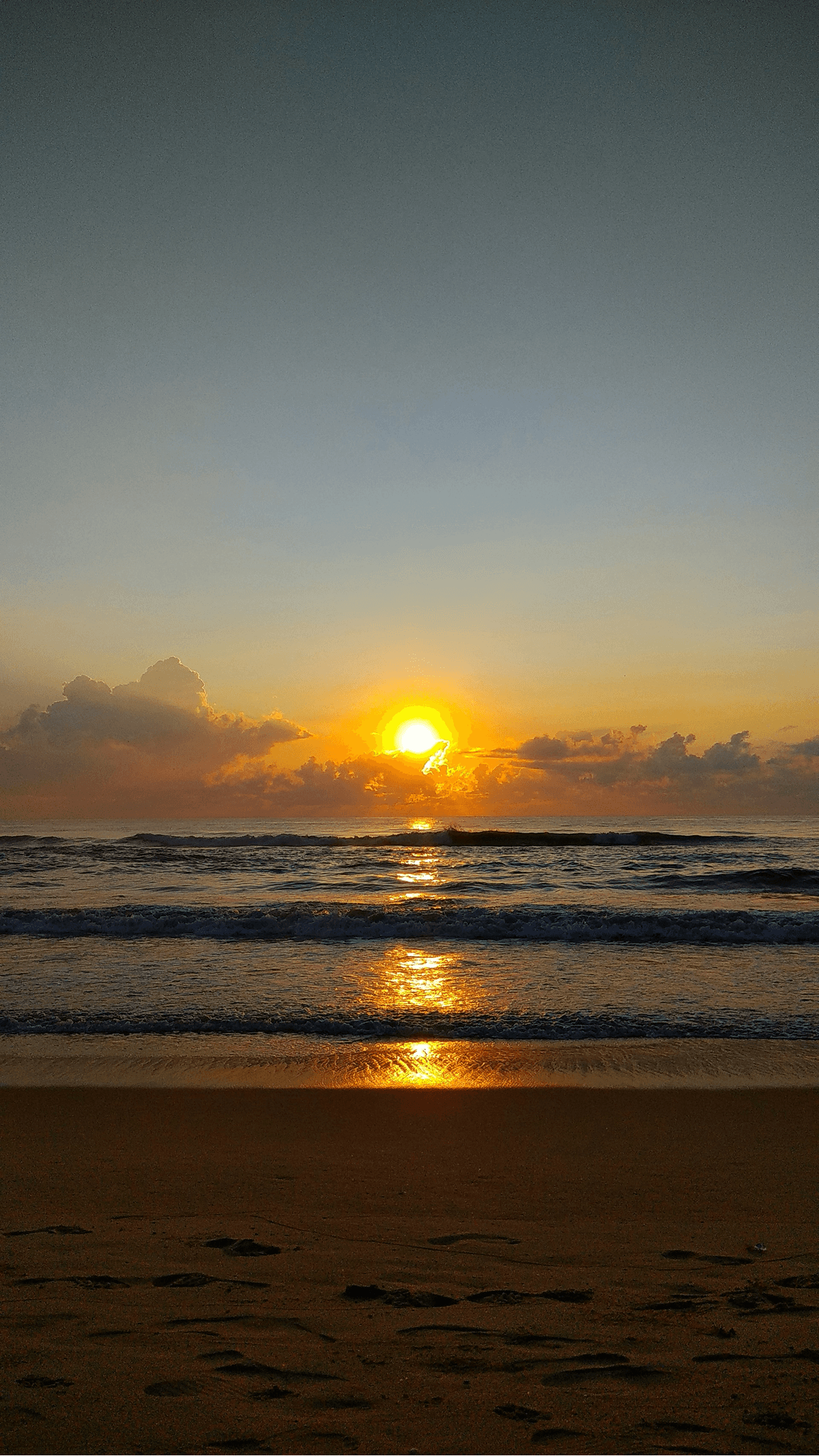 Image of a sunrise over the ocean in Chennai with waves and golden light.