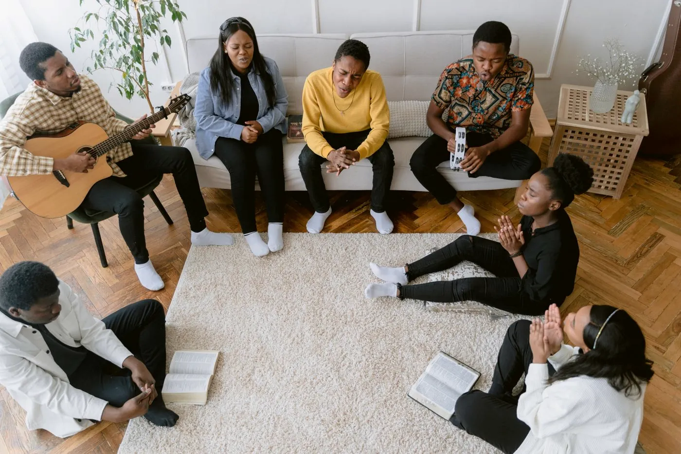 A small group sitting in a circle in a living room with open Bibles