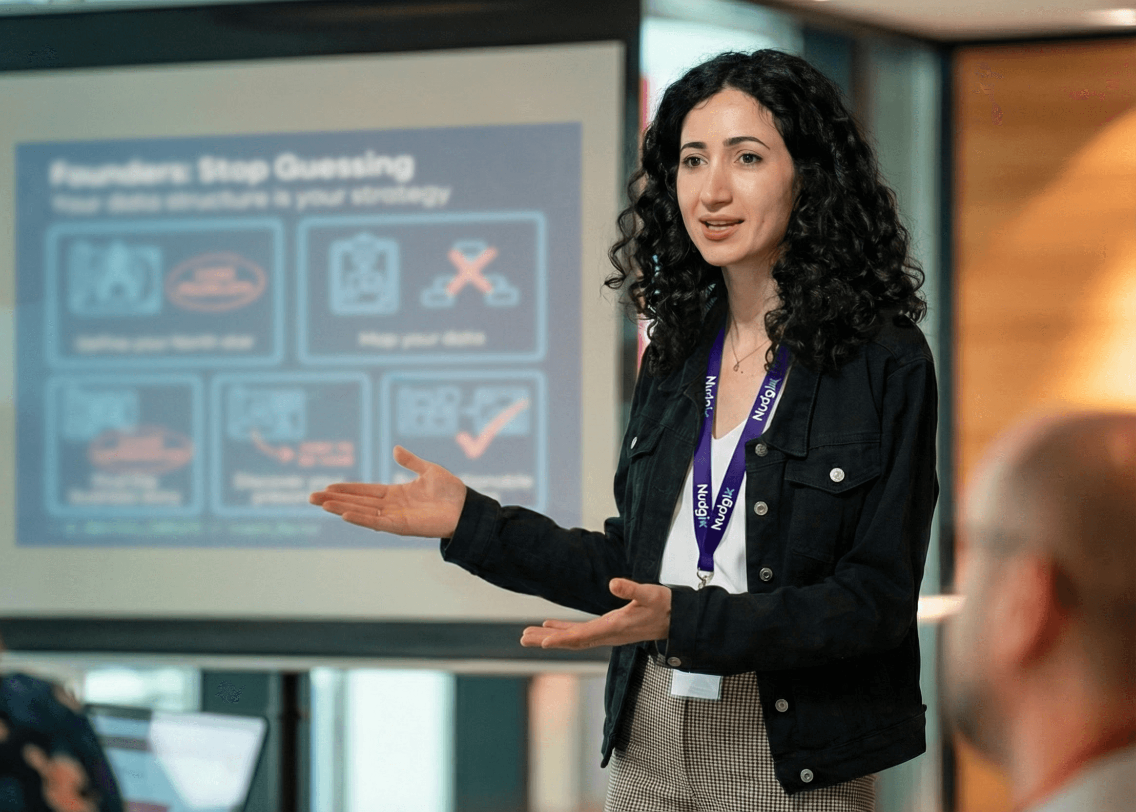 Product design strategist presenting to founders on how to transform complex technology into an investable asset for pre-seed and seed fundraising. The presentation slide, titled 'Founders: Stop Guessing,' focuses on defining a north star and mapping data to improve UX/UI strategy and prepare the MVP for investors