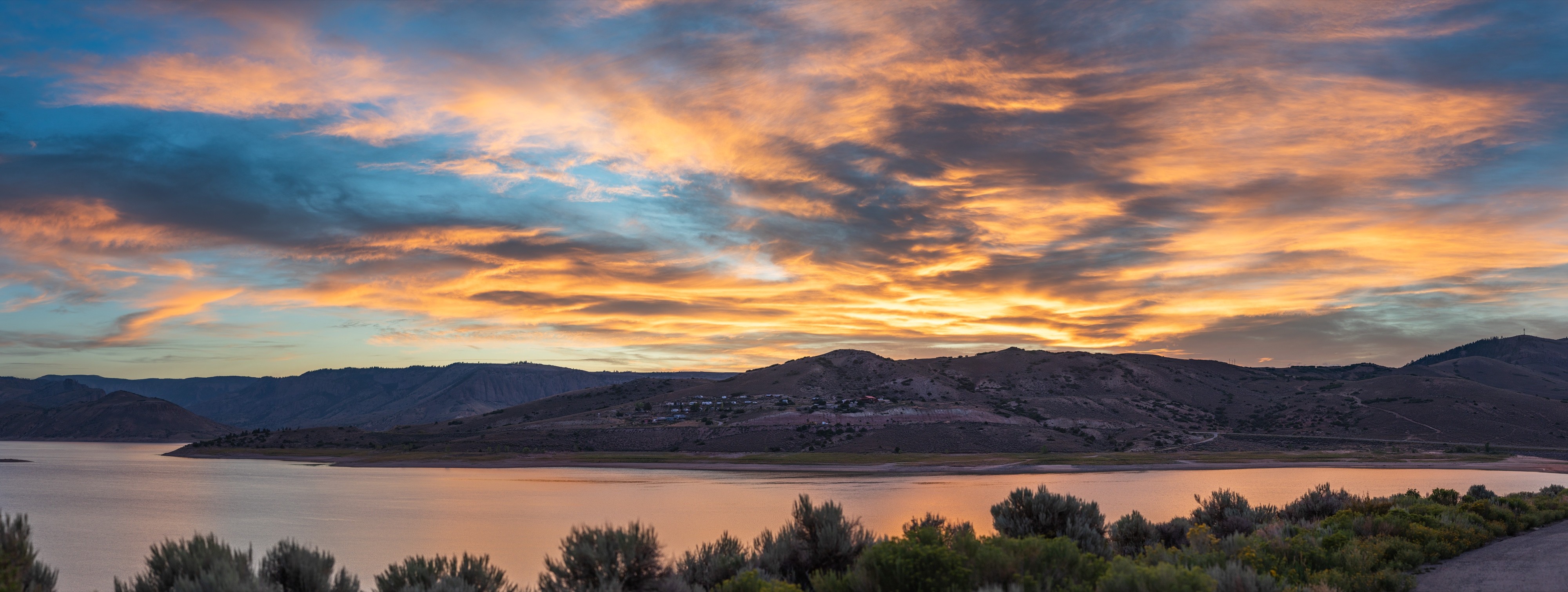 Panoramic landscape photograph of mountains, water, desert, or coast by Lucas Jensen