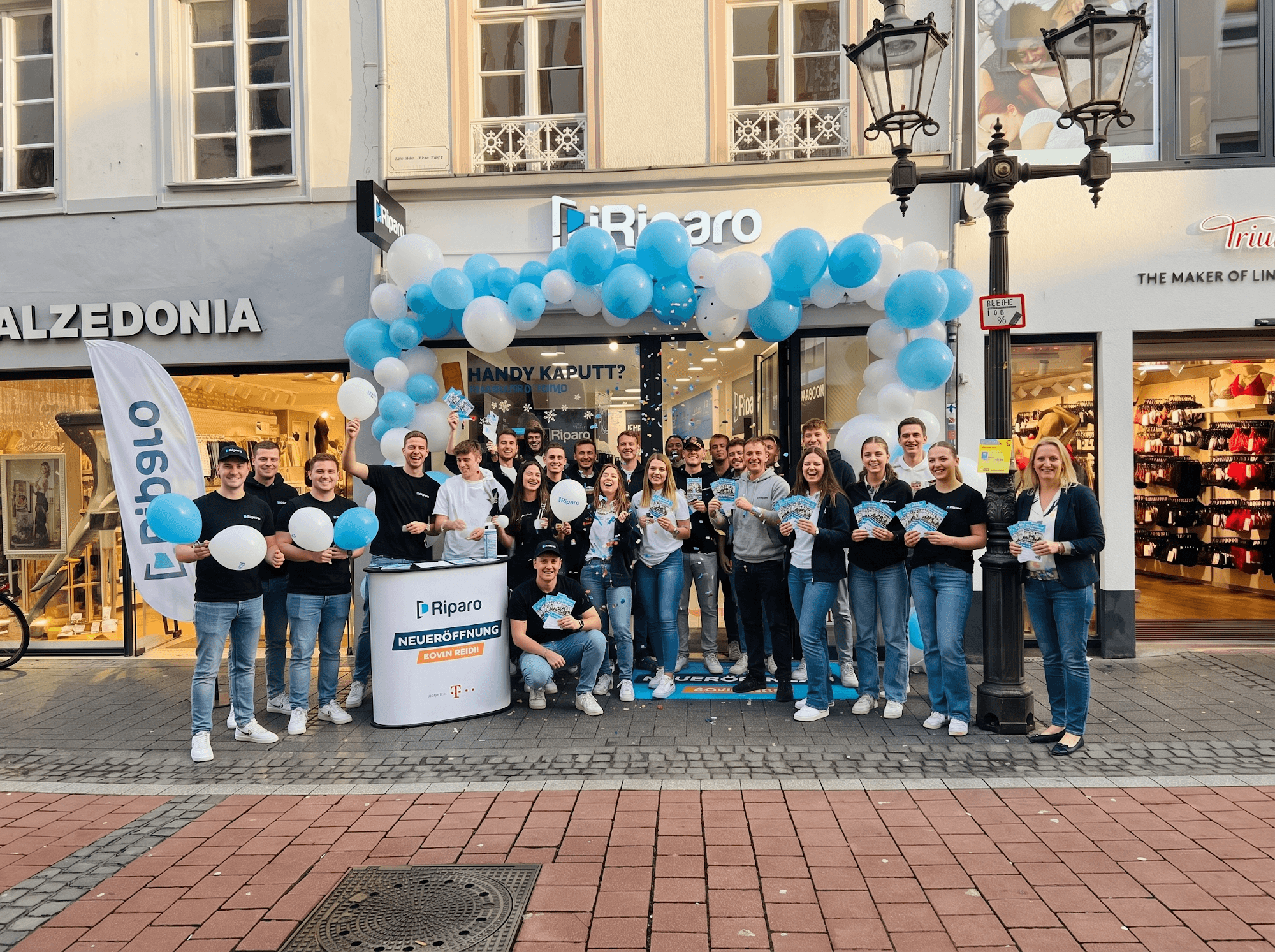iRiparo team outside a store opening with balloons
