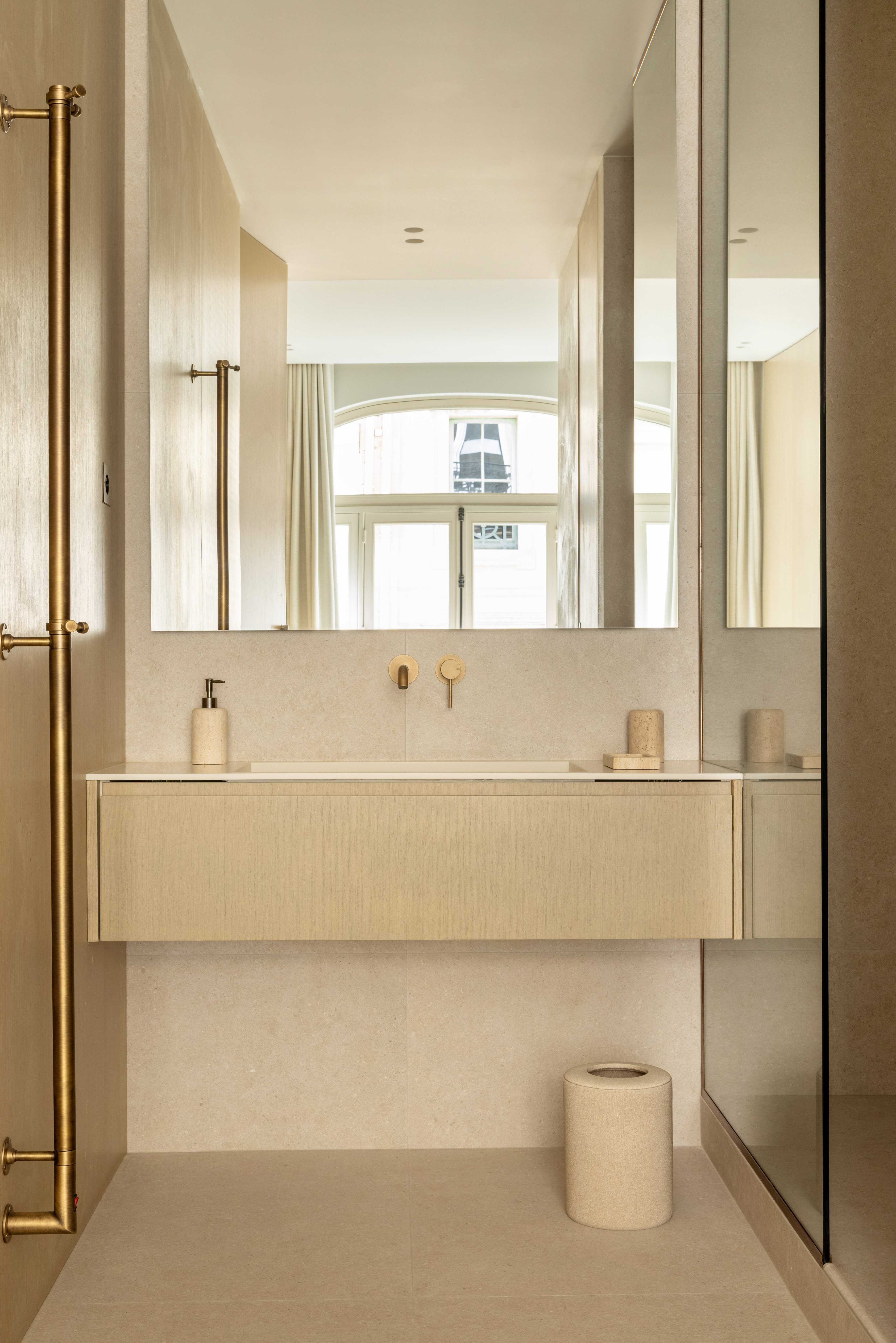 Salle de bain epuree avec vasque suspendue, miroir encadre, robinetterie doree et seche-serviettes dore