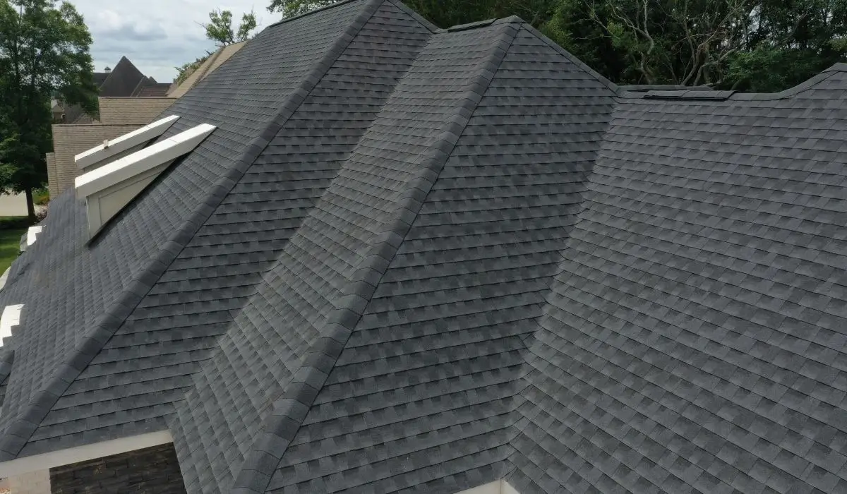 A professionally installed dark gray asphalt shingle roof on a residential home, showing clean lines, multiple peaks, and skylight windows.