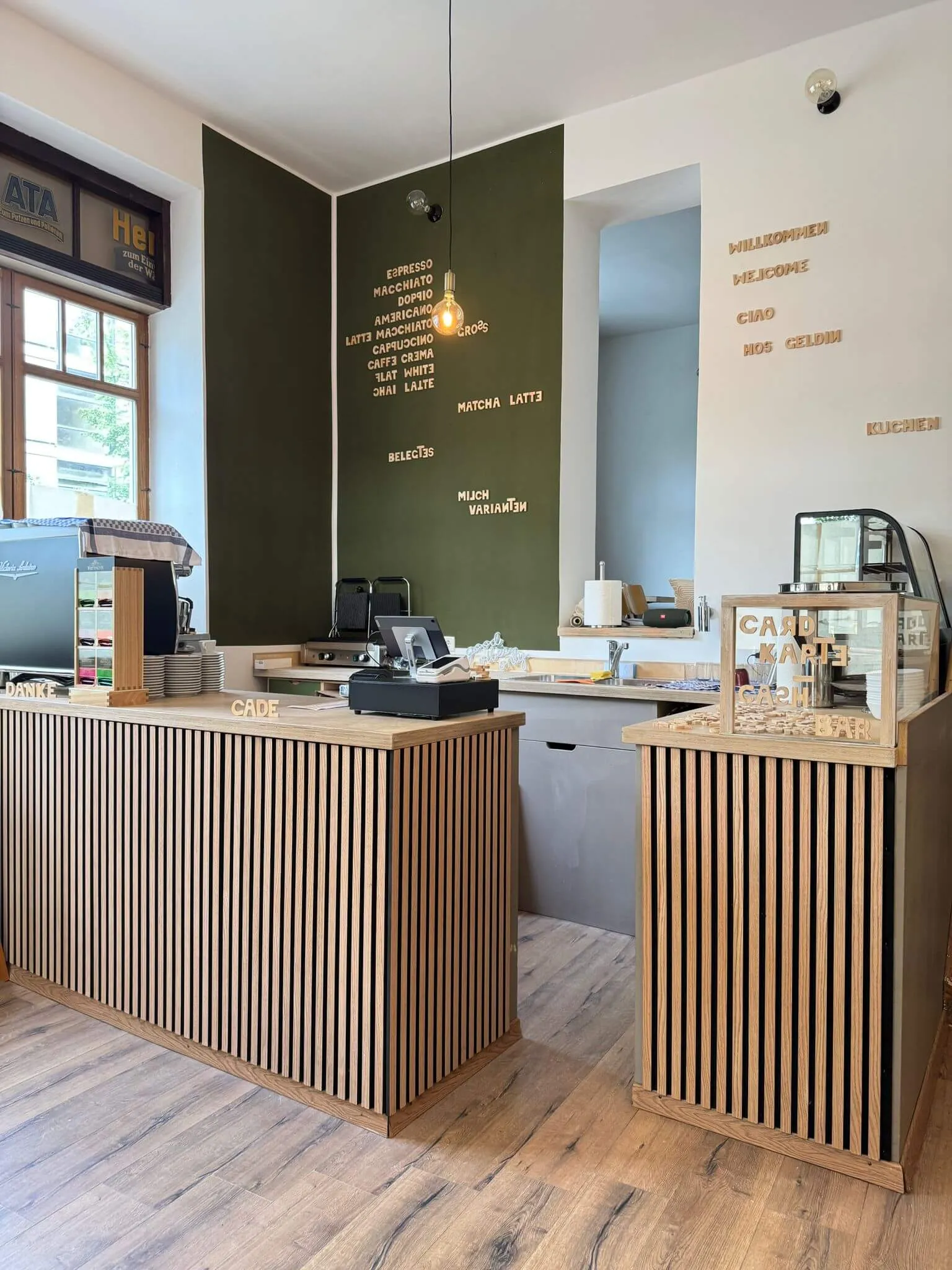 A modern office space featuring a wooden reception desk and green accent wall with decorative elements.