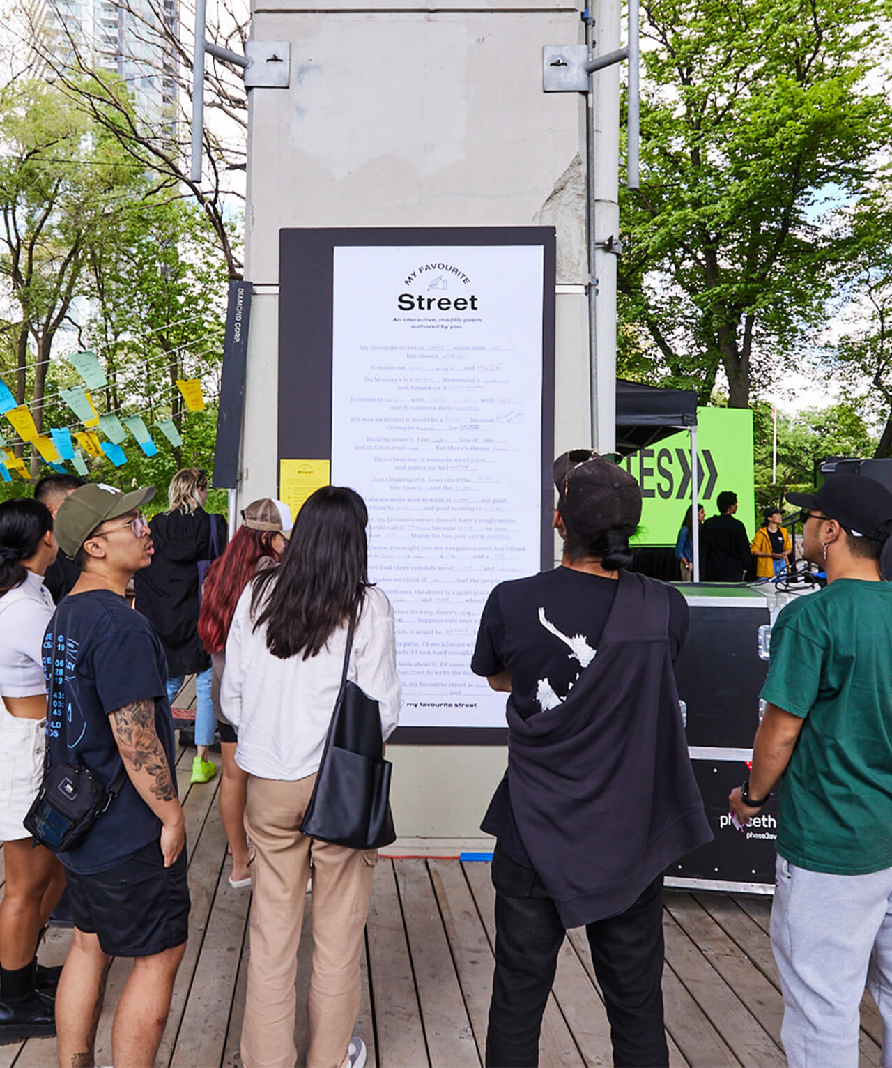 A group of people standing around a pillar with a large poster titled "My Favourite Street"