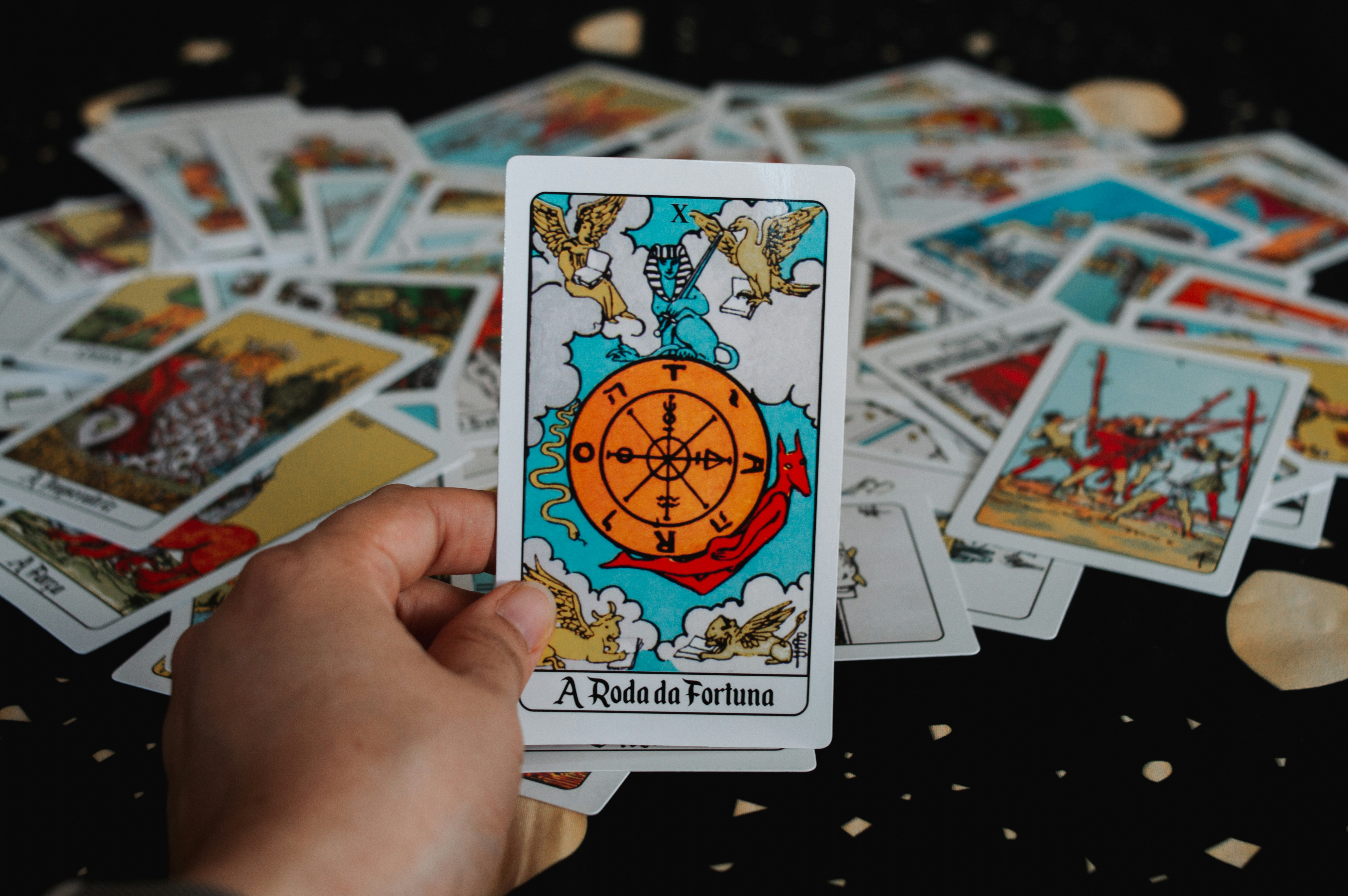 Hand holding a tarot card with wheel of fortune.