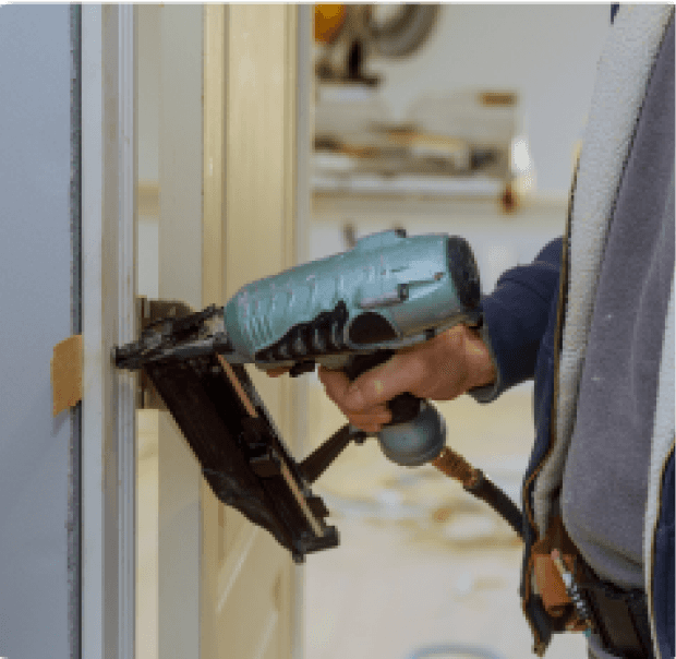 Carpenter using a nail gun on a wooden surface.