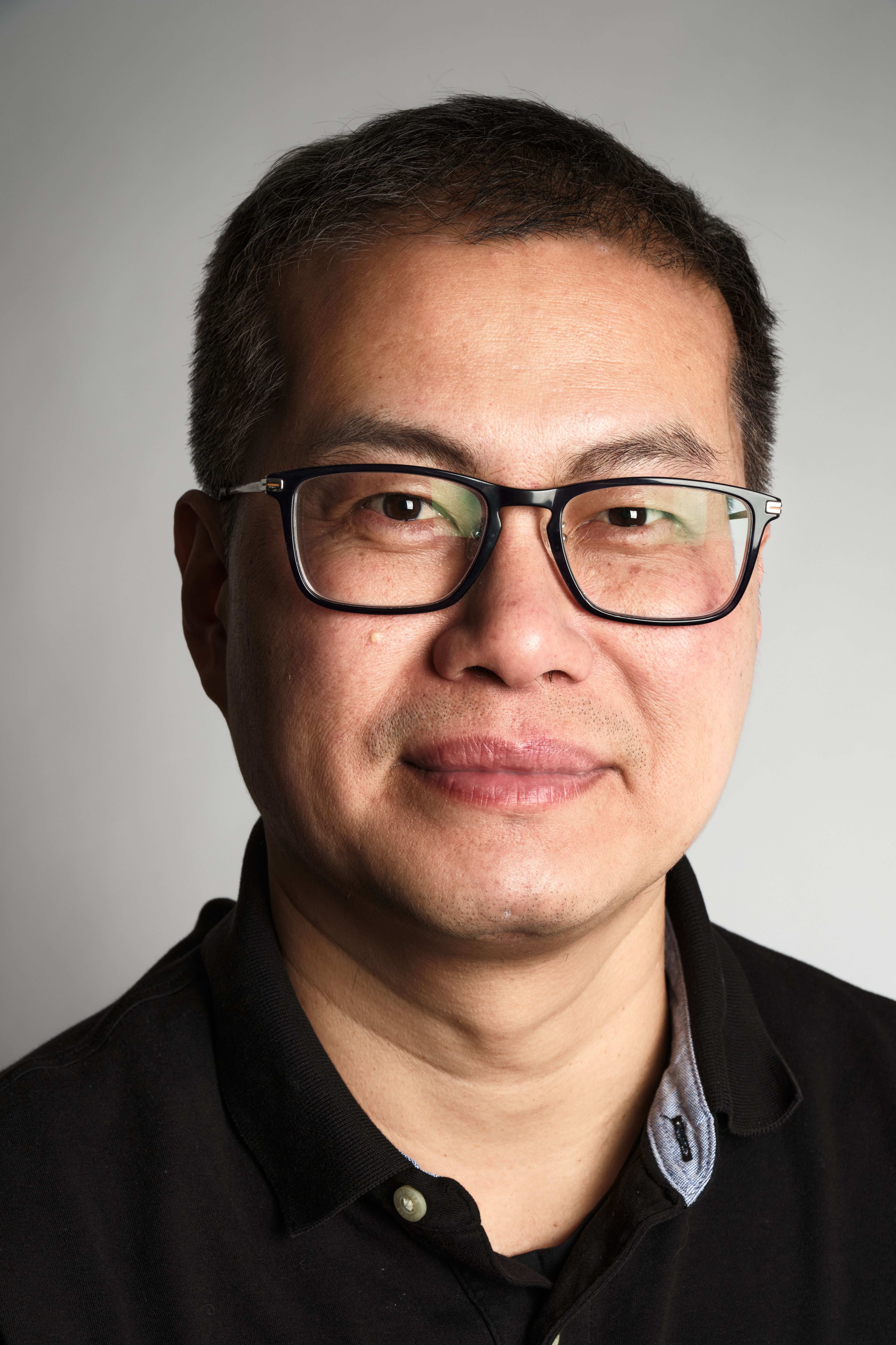 Man headshot wearing specs with a subtle smile in his face