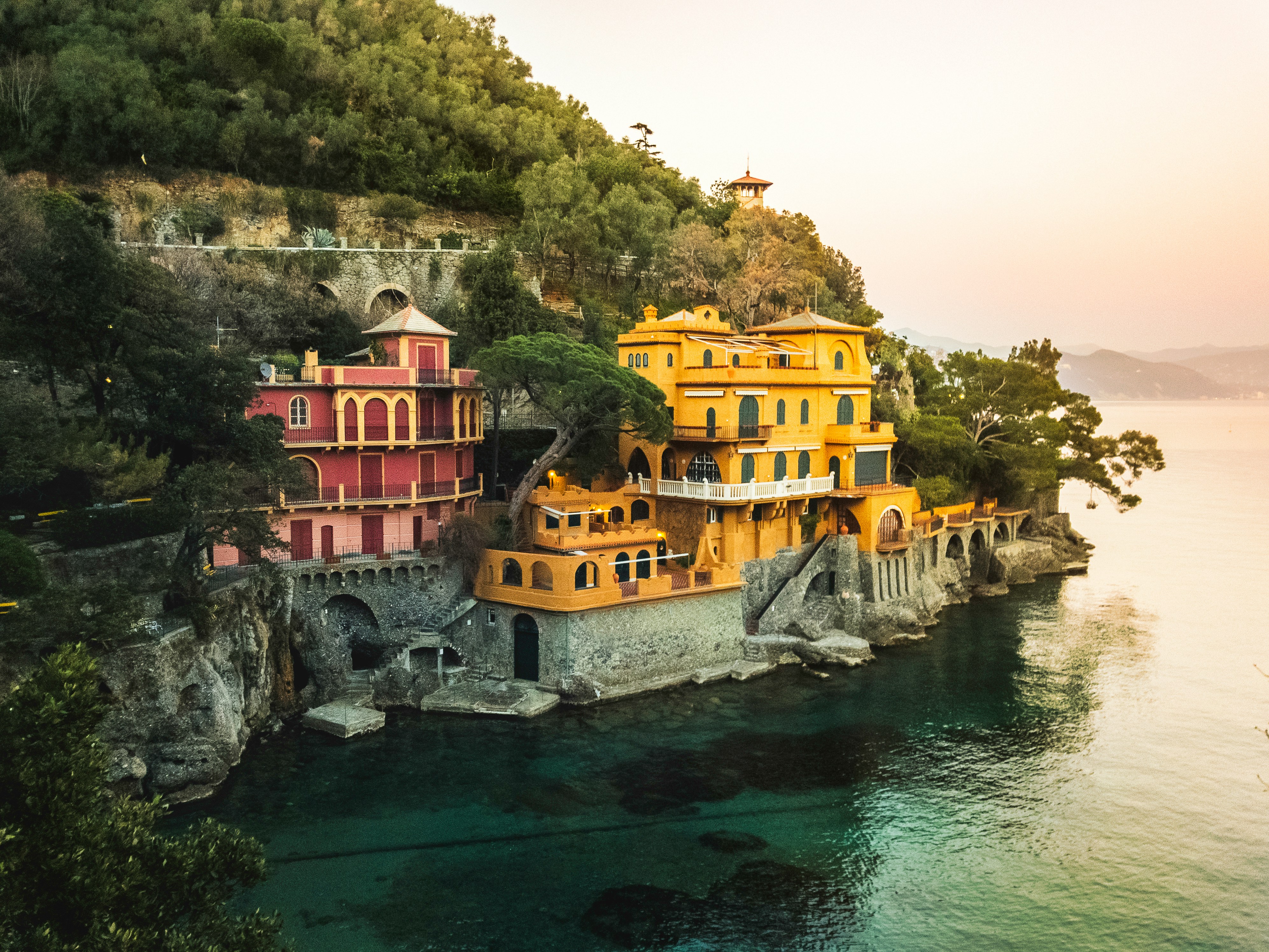 yellow concrete building beside body of water surrounded with green trees at daytime