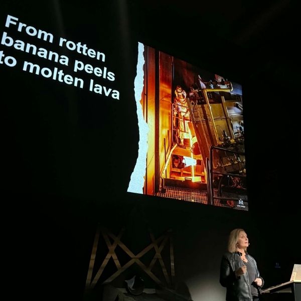 A woman presents on stage at Lava Show with a large screen behind her displaying the text “From rotten banana peels to molten lava” alongside an image of an industrial process, during an Innovation Week event in Reykjavík.