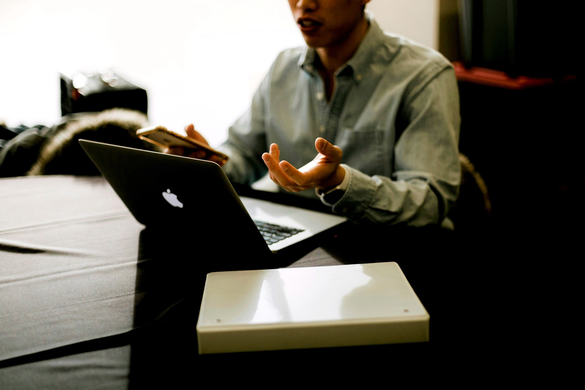 Mid-section view of person in front of laptop working and holding cellphone.