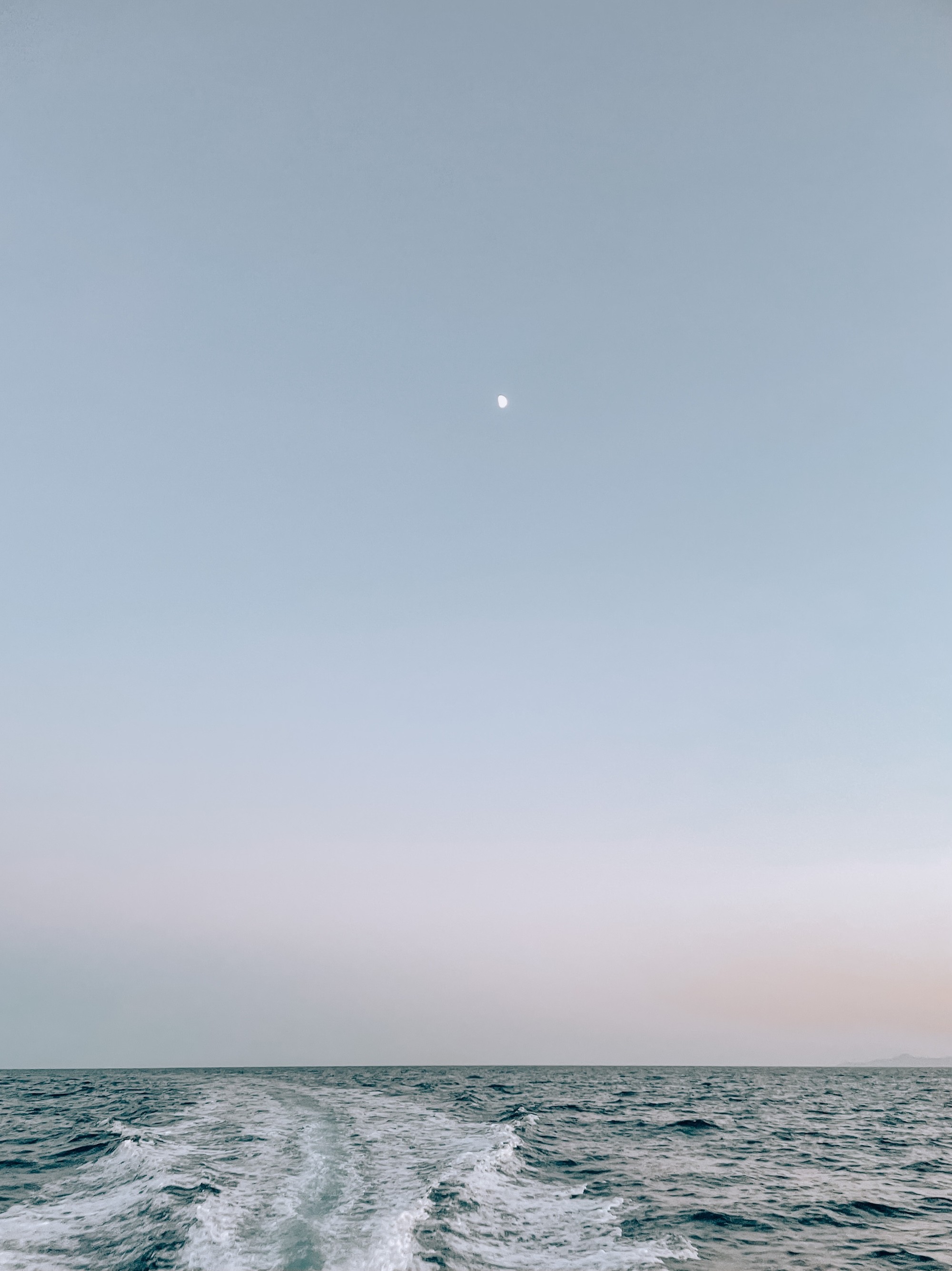 Sunset photo of the sea and the sky as the motorboat creates waves behind us.