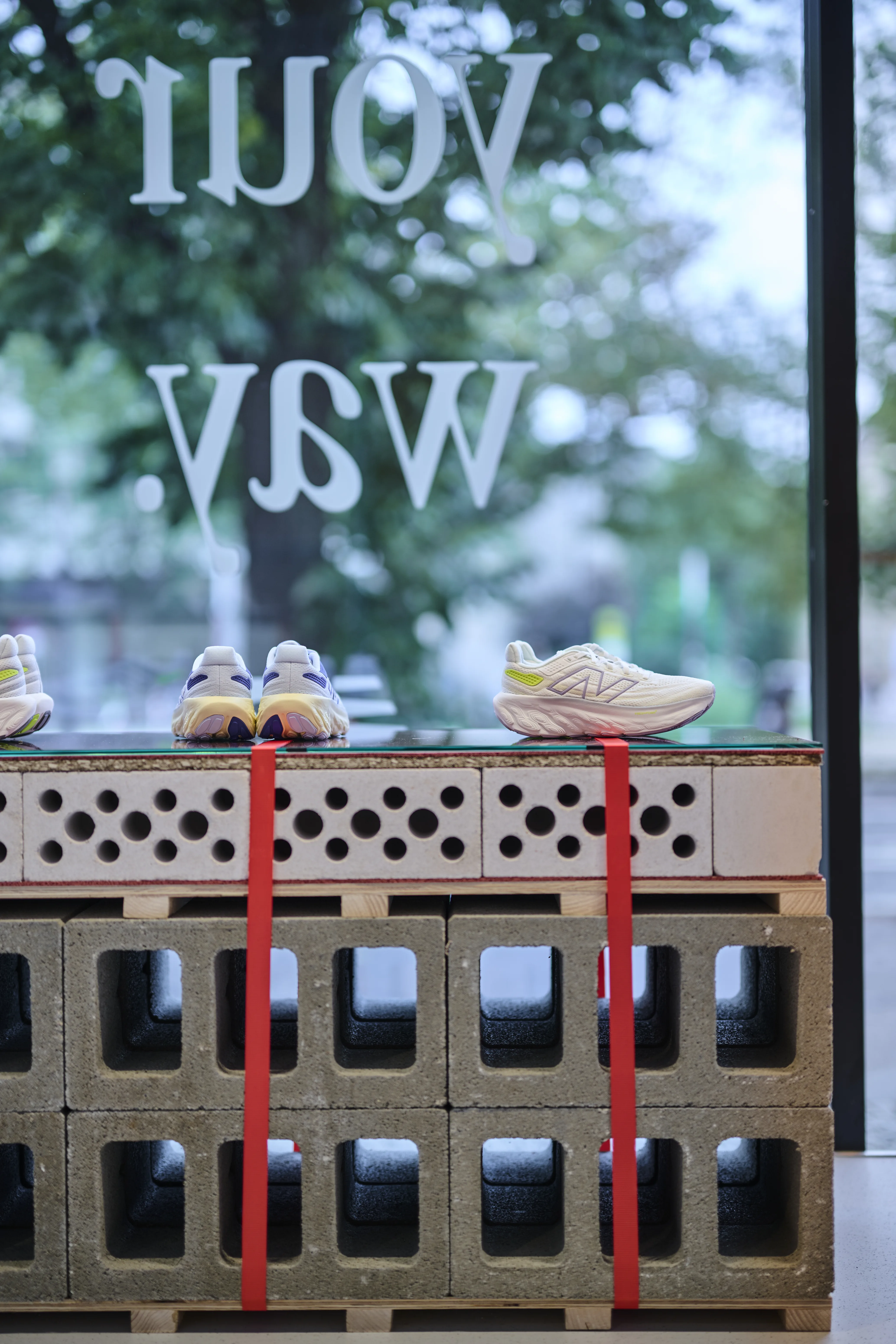 New Balance running shoes presented on perforated bricks with red straps in the shop window with Your Way lettering.