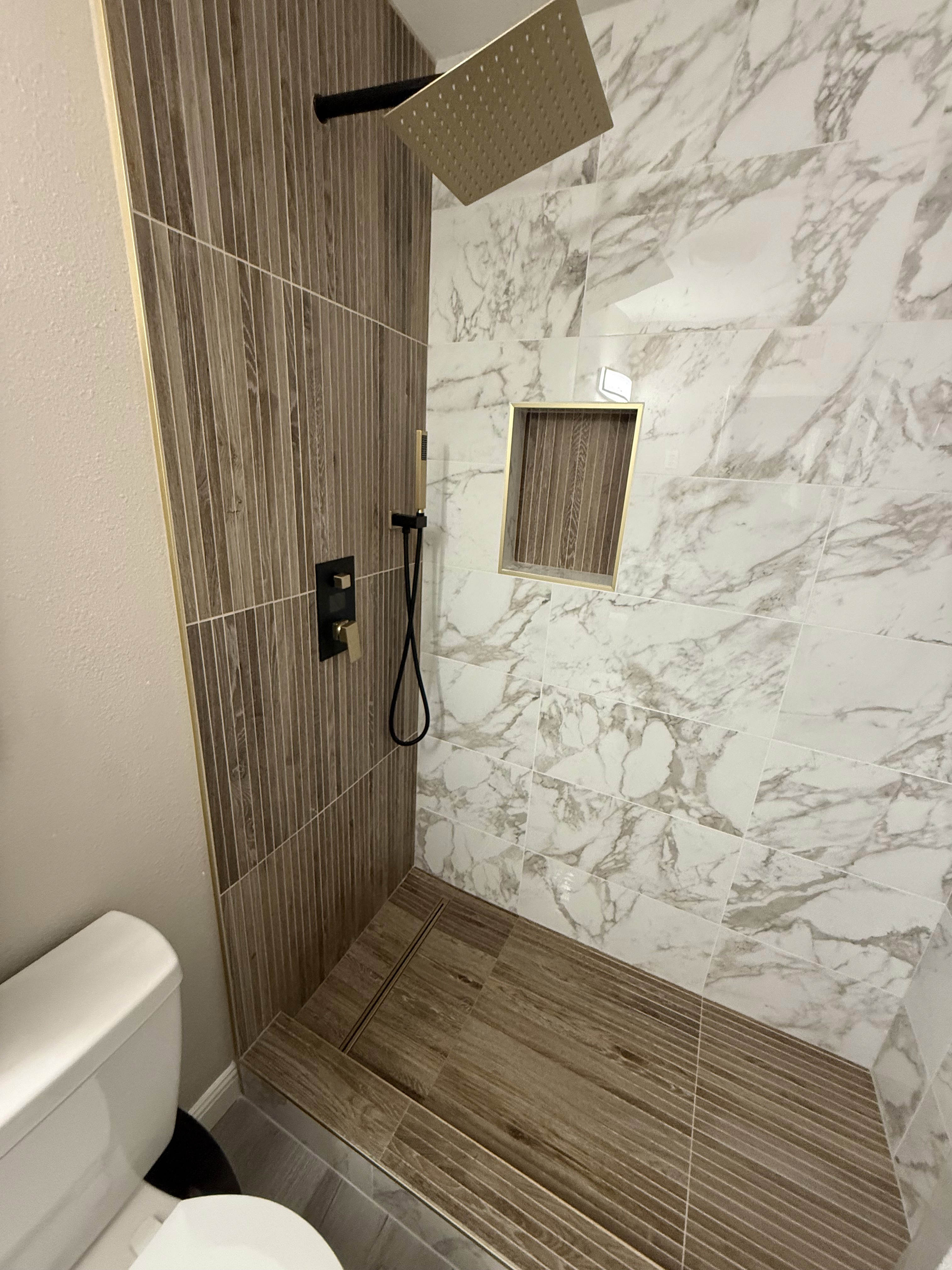 Luxurious bathroom vanity area with a dramatic wall featuring large format natural stone tiles in varying earthy tones and complex veining, serving as a striking backsplash above a double sink vanity.