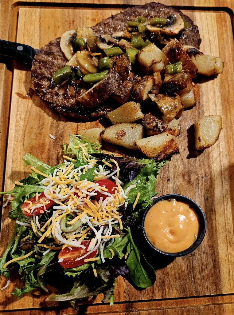 Juicy steak with a side of fresh vegetables served on a wooden cutting board at Dueling Pistols Restaurant.