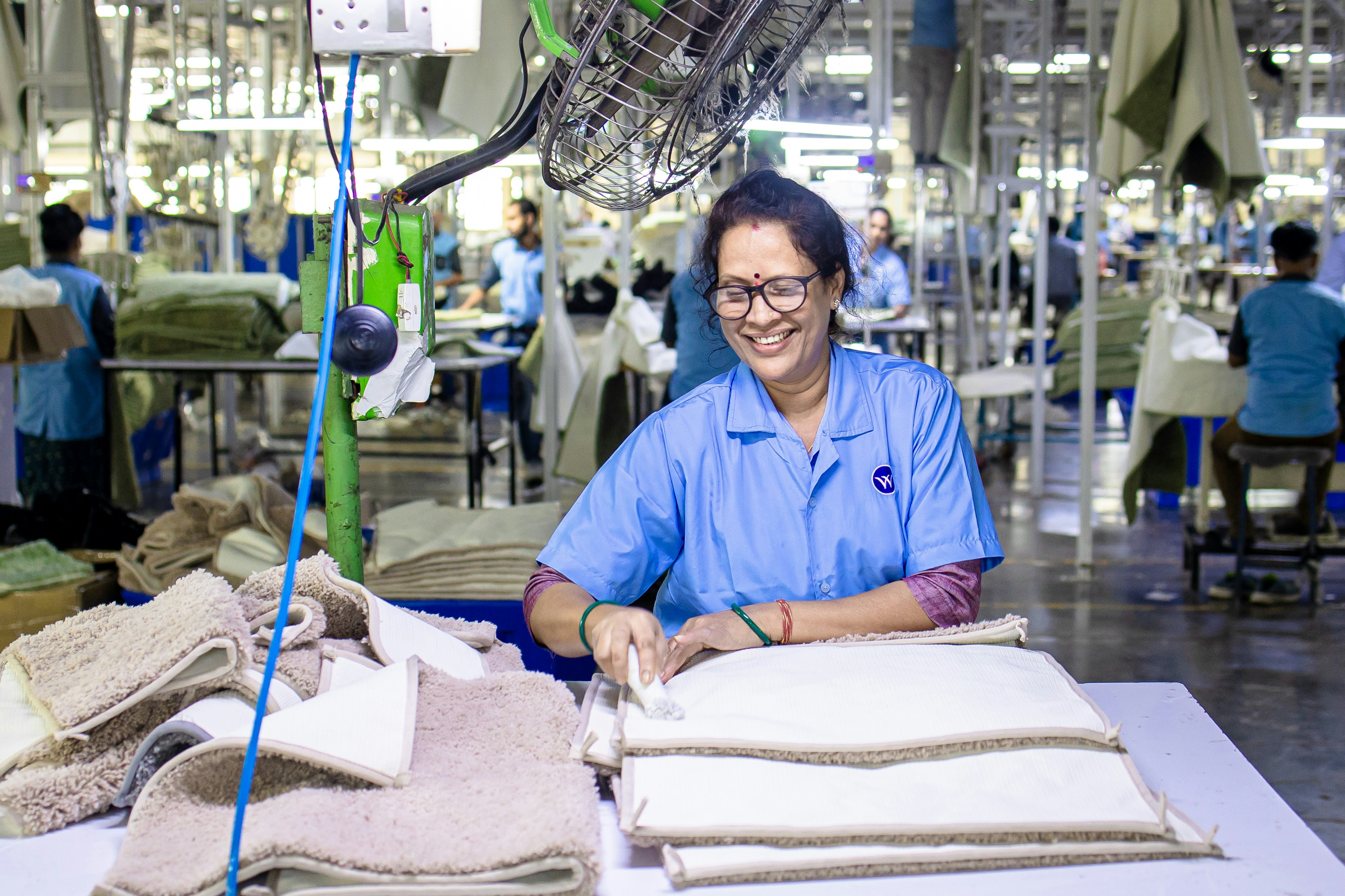 Woman works at a textile factory, smiling and happy.